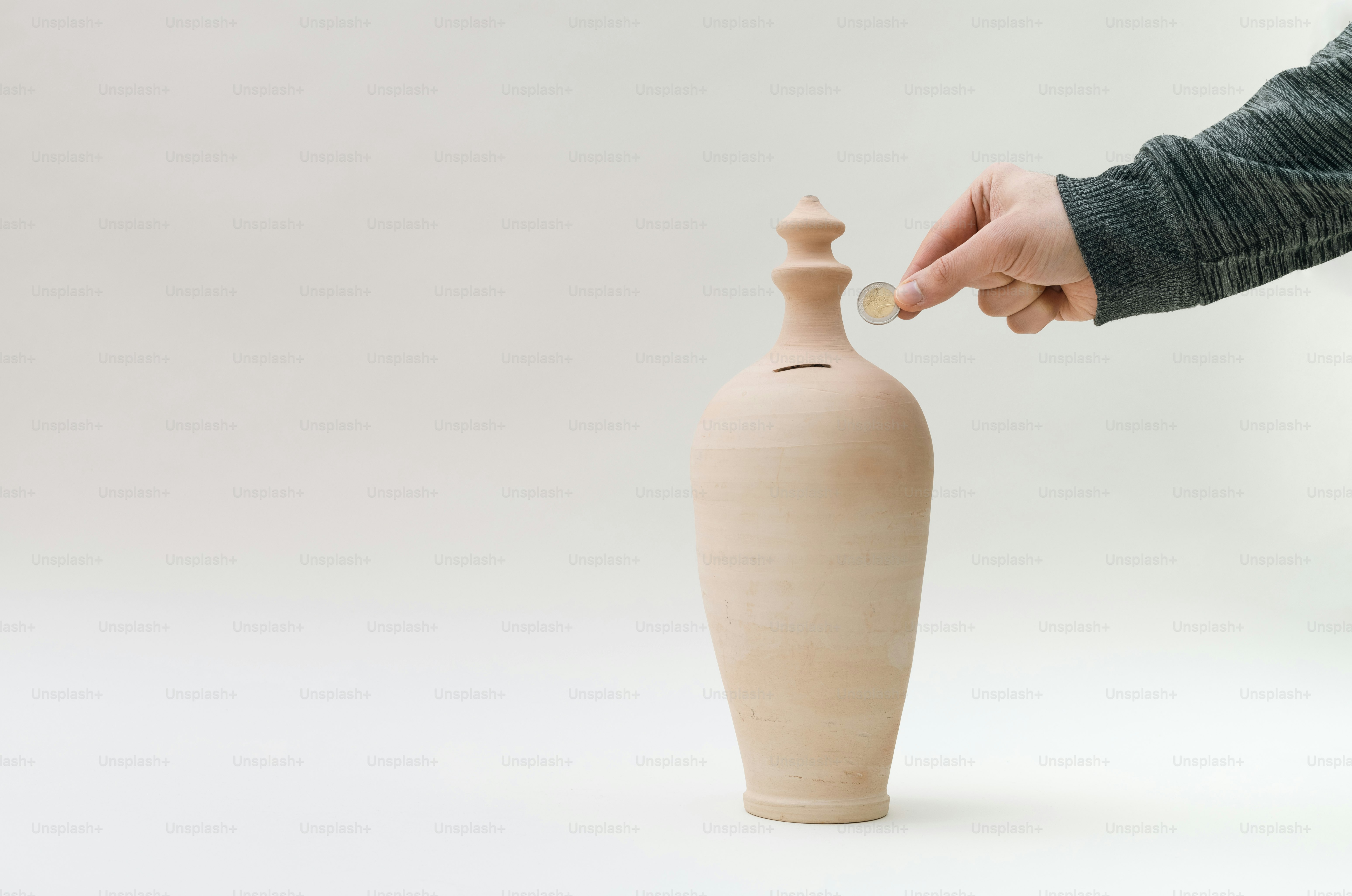 eine Person, die eine Münze in eine Vase legt