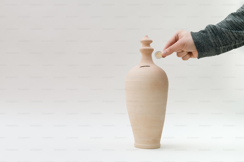 a person putting a coin into a vase