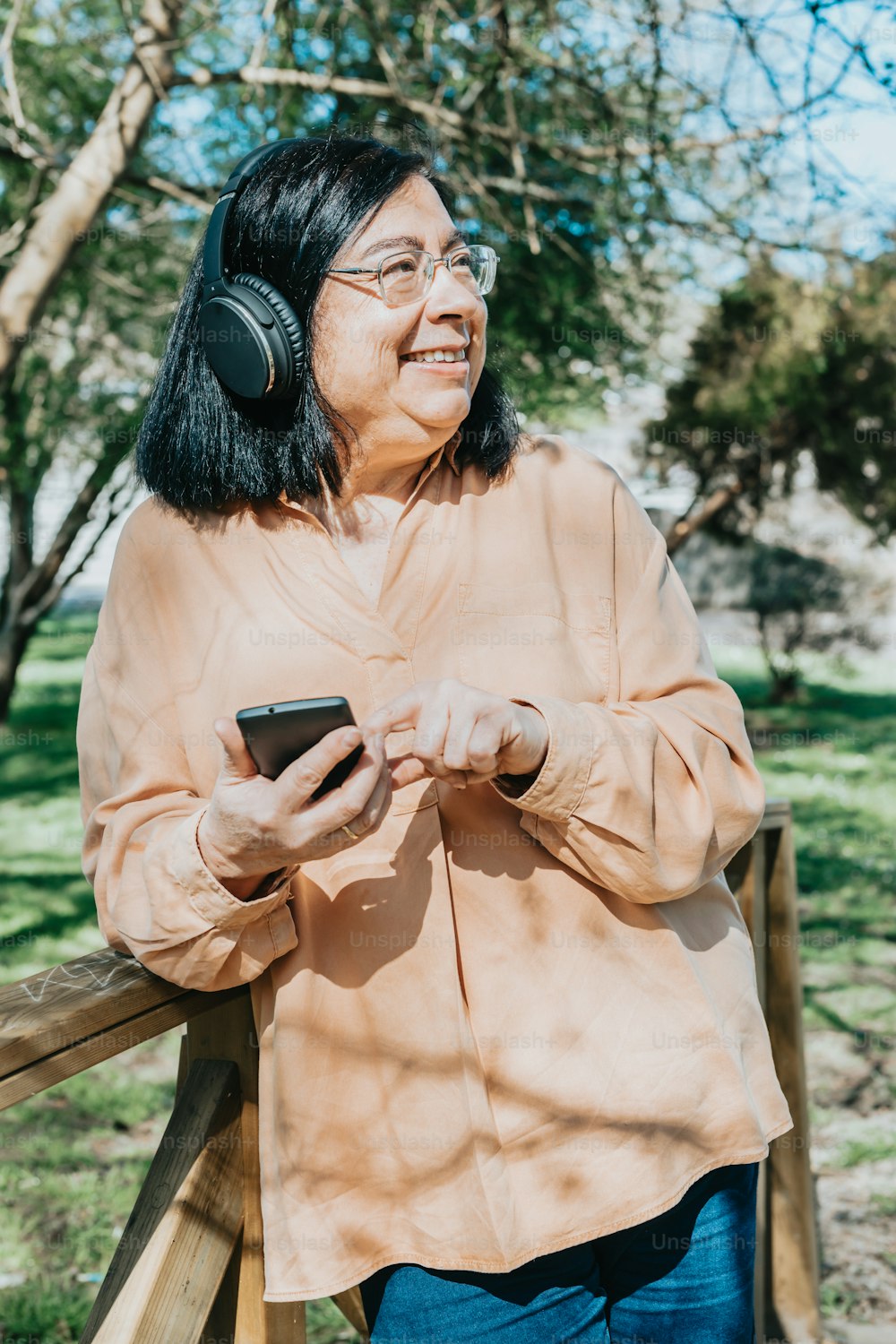 Eine Frau mit Kopfhörern schaut auf ihr Handy