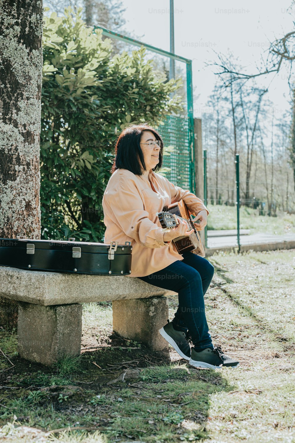 a woman sitting on a cement bench holding a guitar
