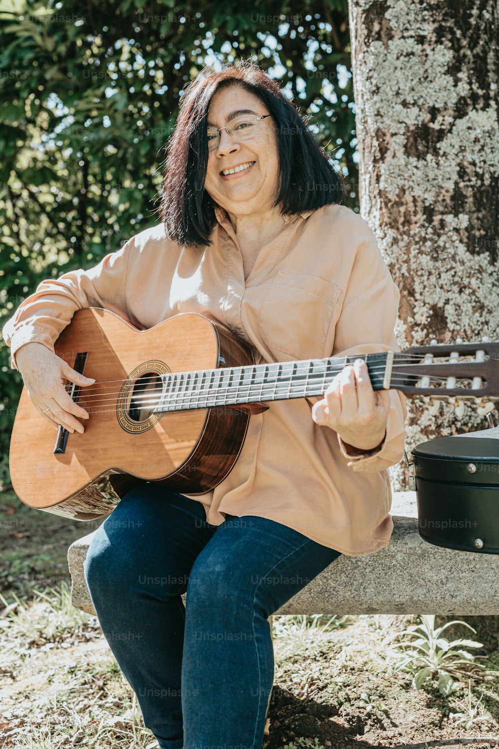 a woman sitting on a bench playing a guitar