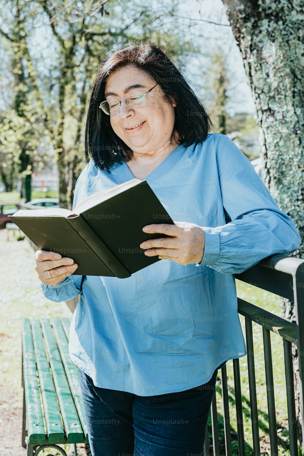 a woman reading a book on a park bench