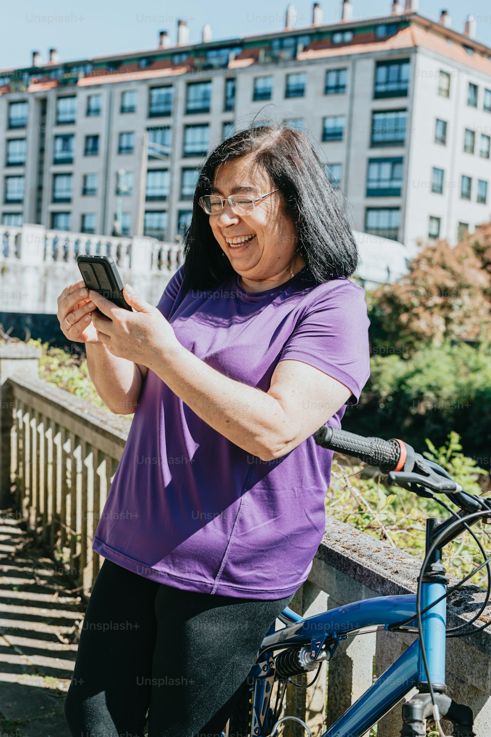 Une femme debout à côté d’un vélo tenant un téléphone portable
