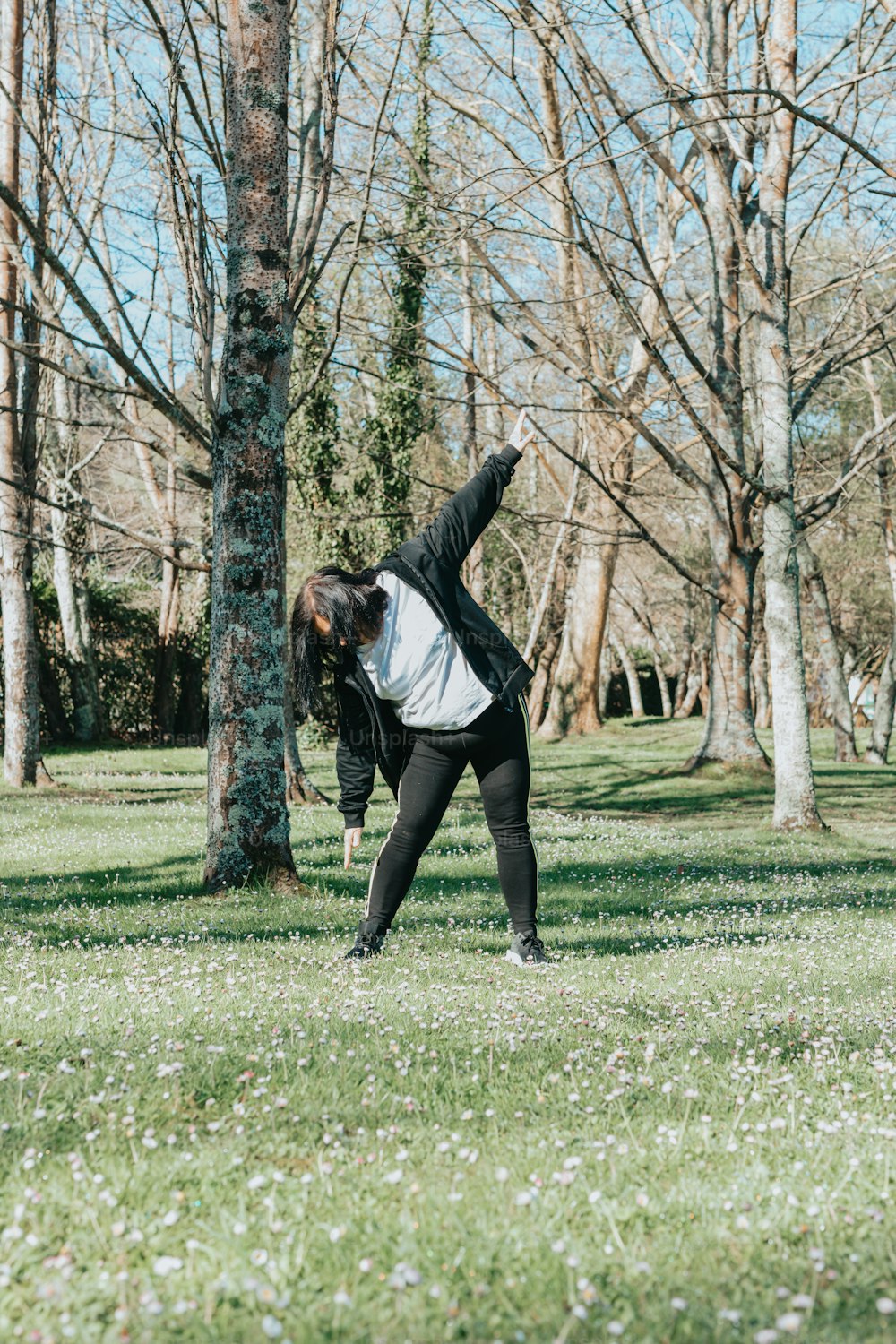 a woman stretching in a park with trees in the background