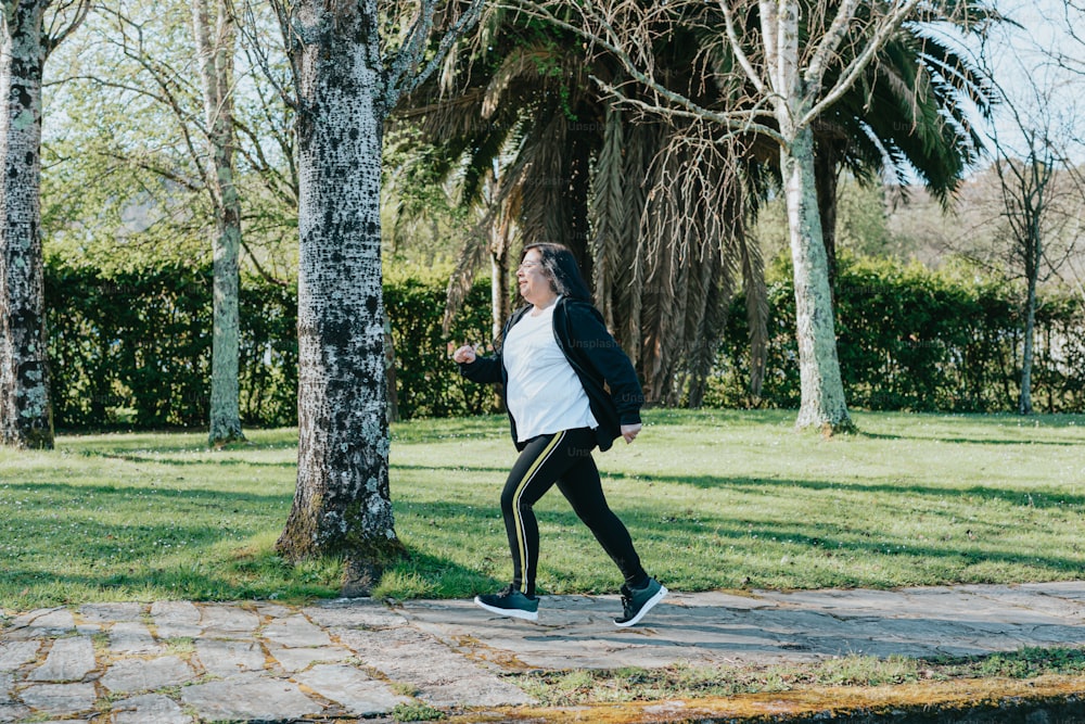 a woman running in a park with trees in the background