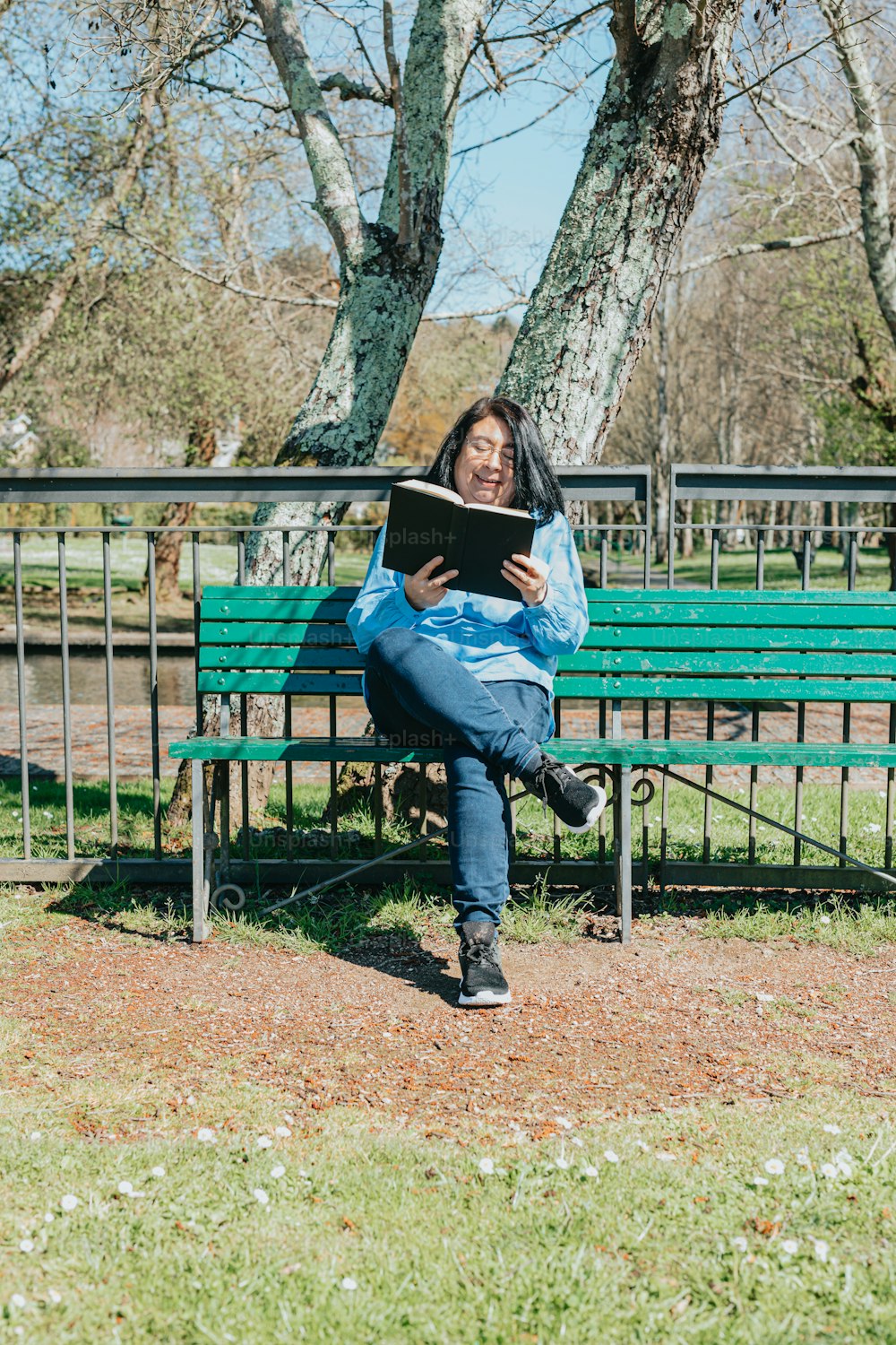 a woman sitting on a bench reading a book