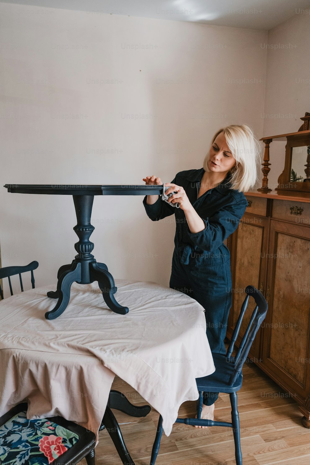 a woman standing at a table with a white table cloth on it