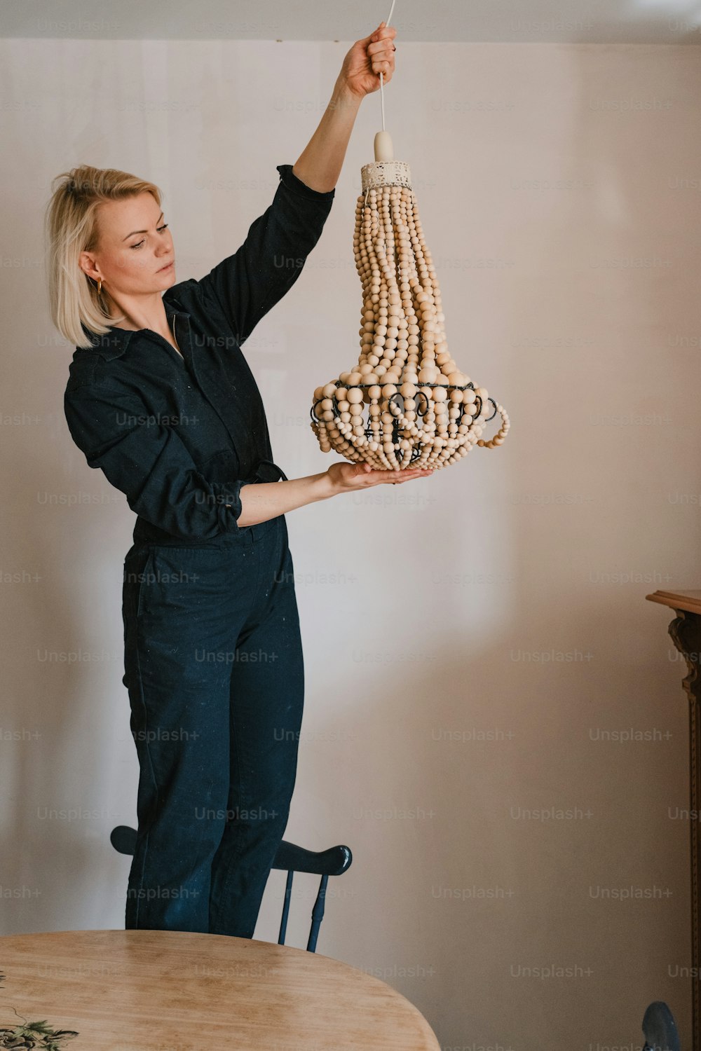 a woman holding a chandelier made of wooden beads