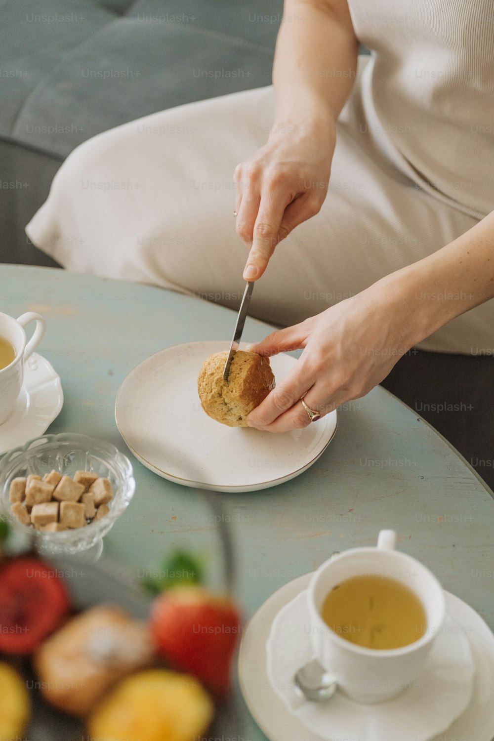 uma pessoa sentada em uma mesa com um prato de comida e uma xícara de chá