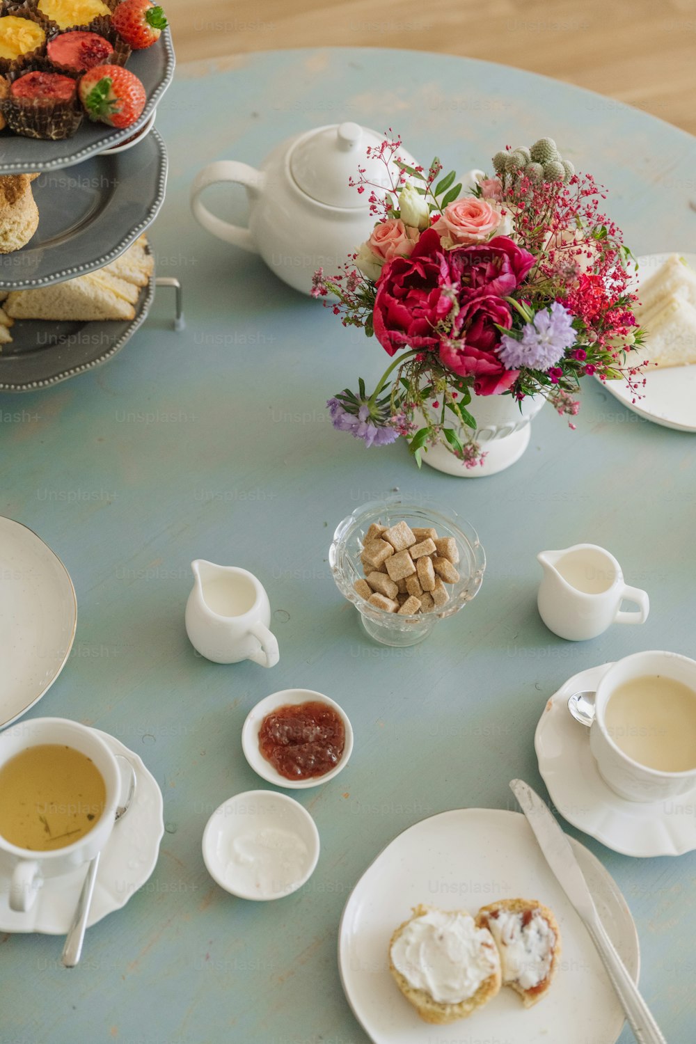 a table topped with plates of food and cups of tea