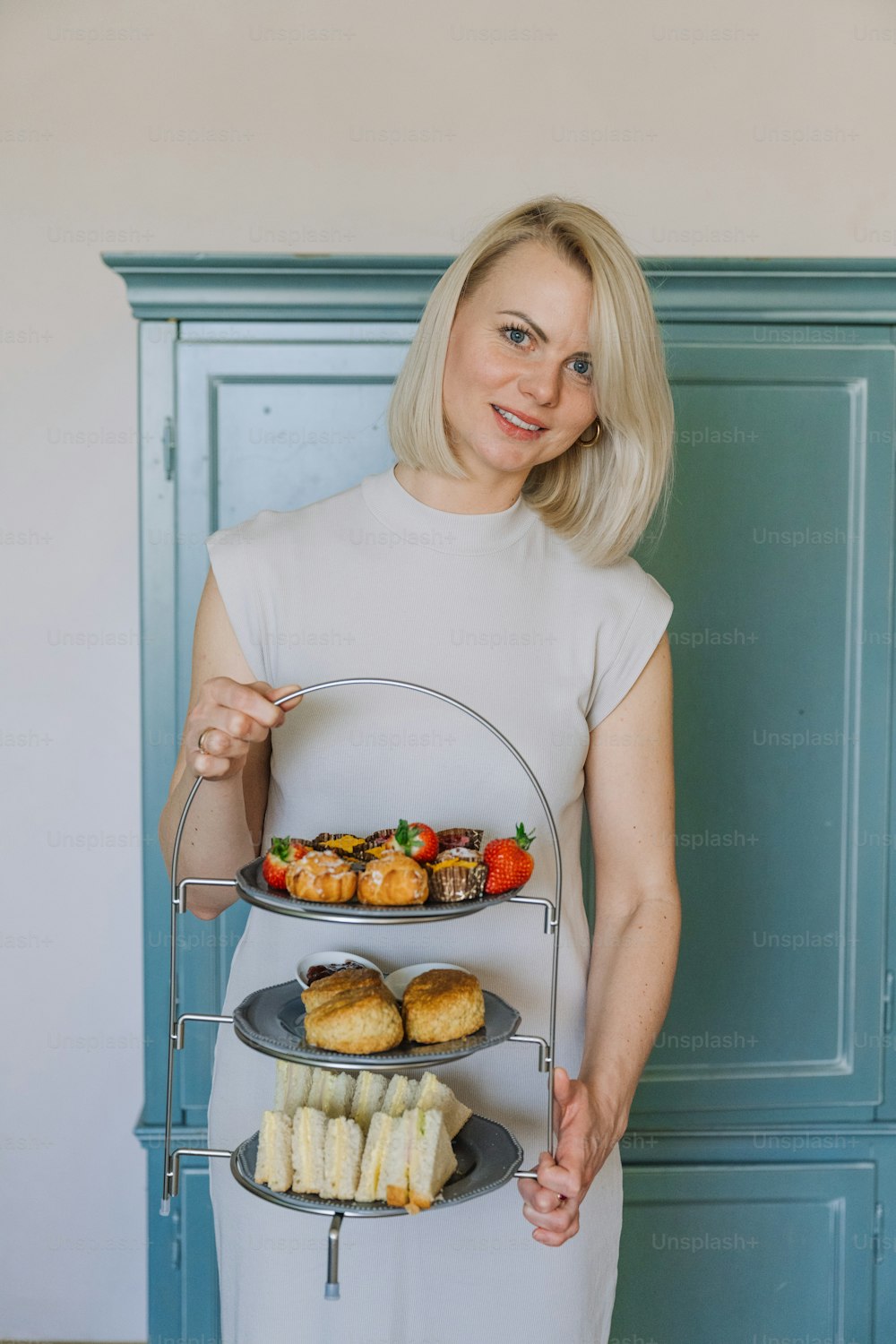 a woman in a white dress holding a tray of food