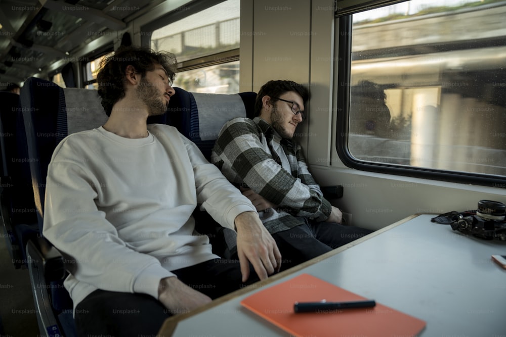 a couple of men sitting next to each other on a train