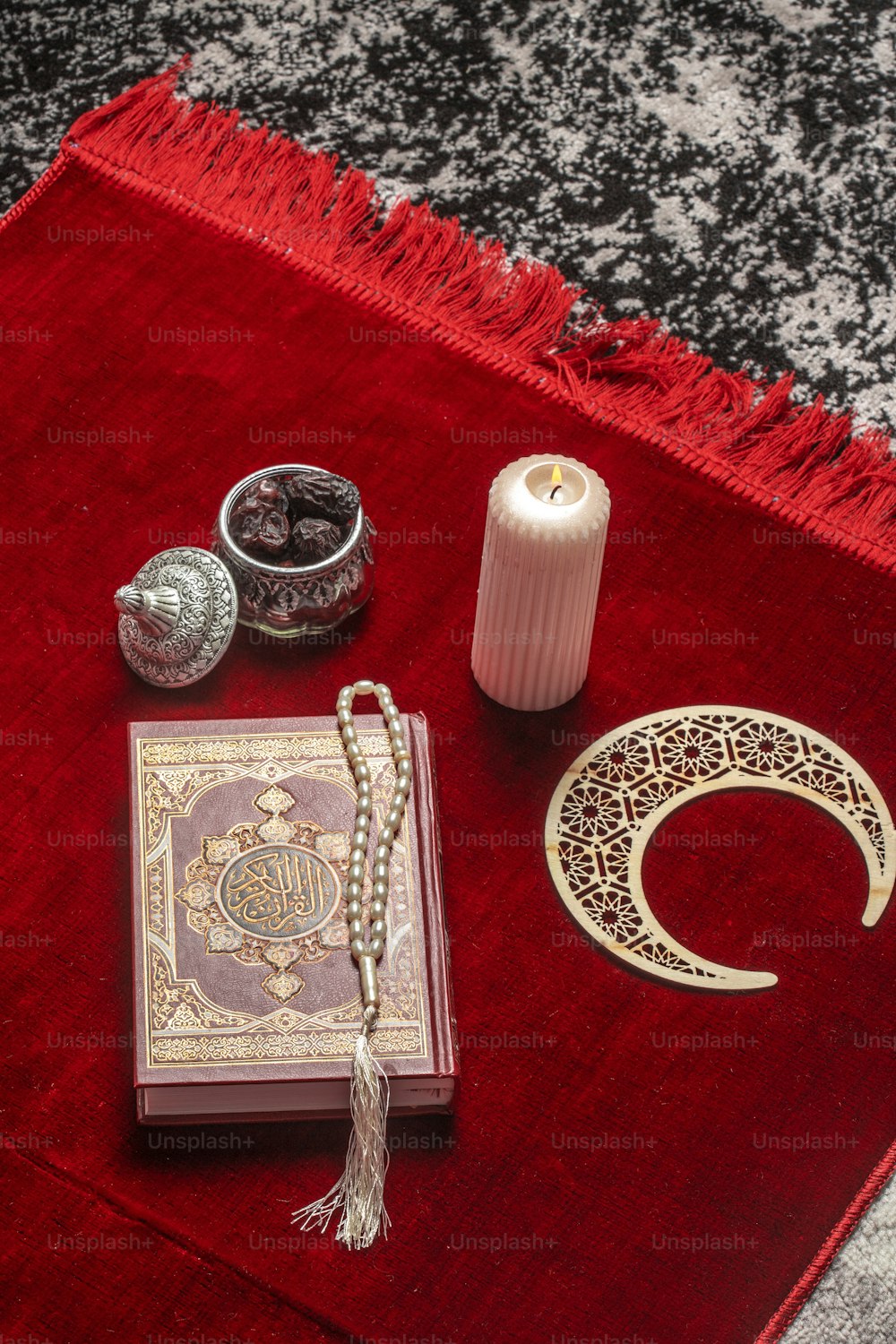 a red rug with a book, candle, and other items on it