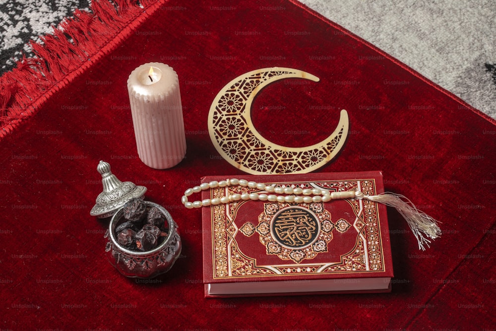 Ein roter Teppich mit einer Kerze, einem Buch, einem Kerzenständer und einem
