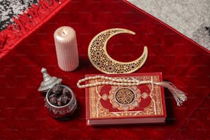 un tappeto rosso con una candela, un libro, un portacandele e un