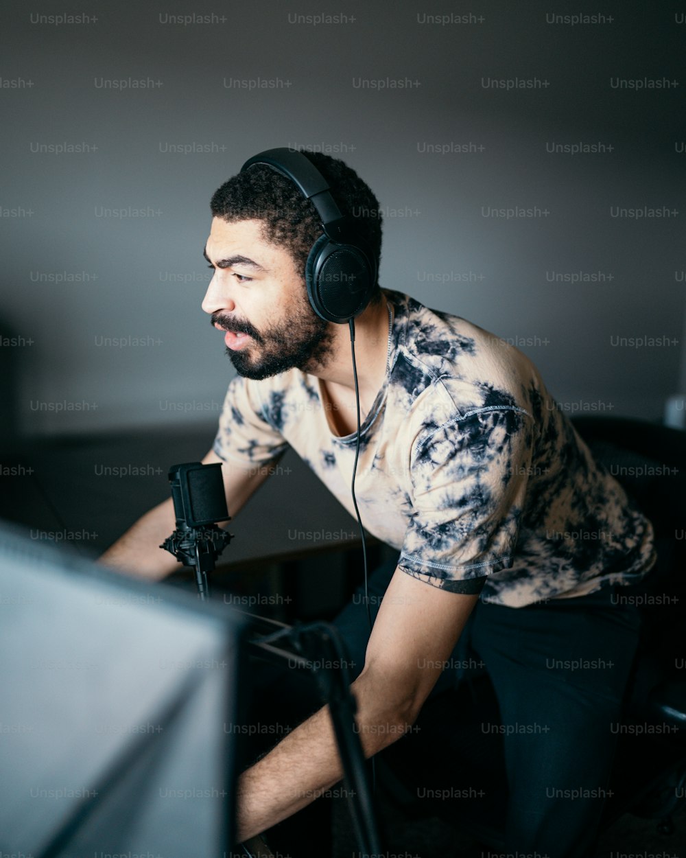 um homem sentado na frente de um computador usando fones de ouvido