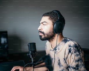 Ein Mann mit Kopfhörern sitzt vor einem Mikrofon