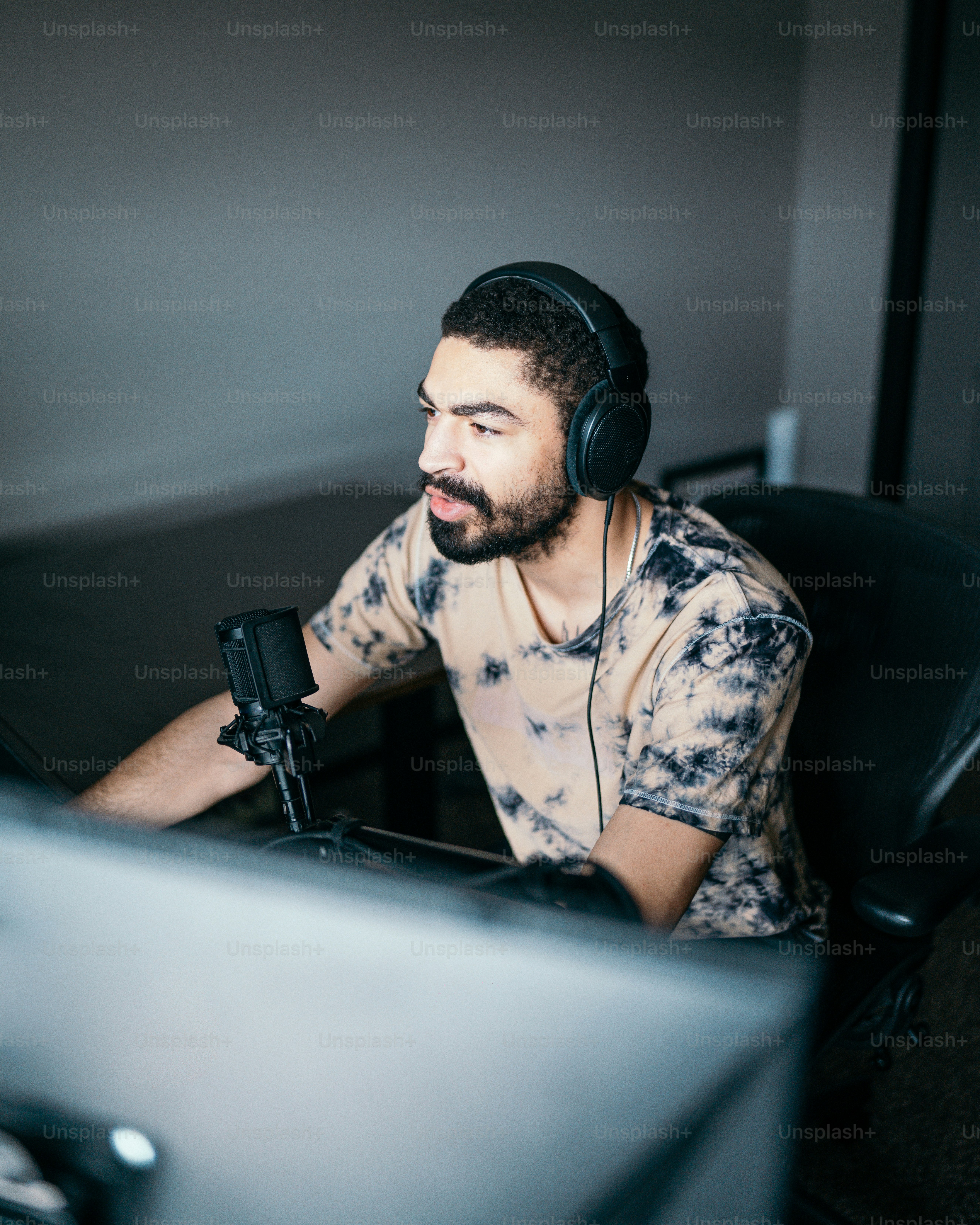 A man sitting in front of a computer wearing headphones photo ...