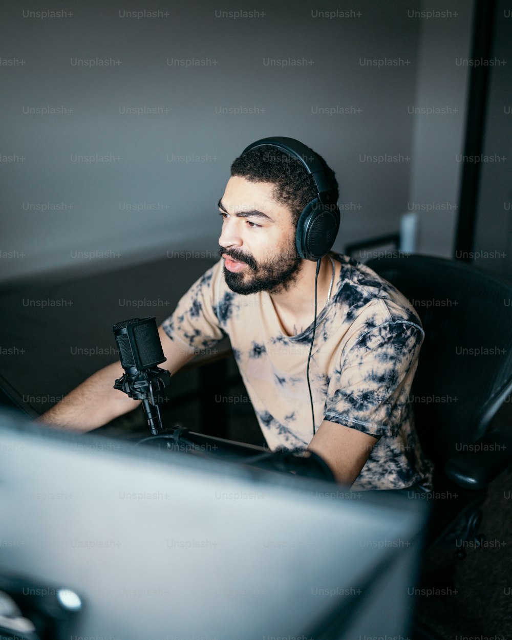 Un hombre sentado frente a una computadora con auriculares