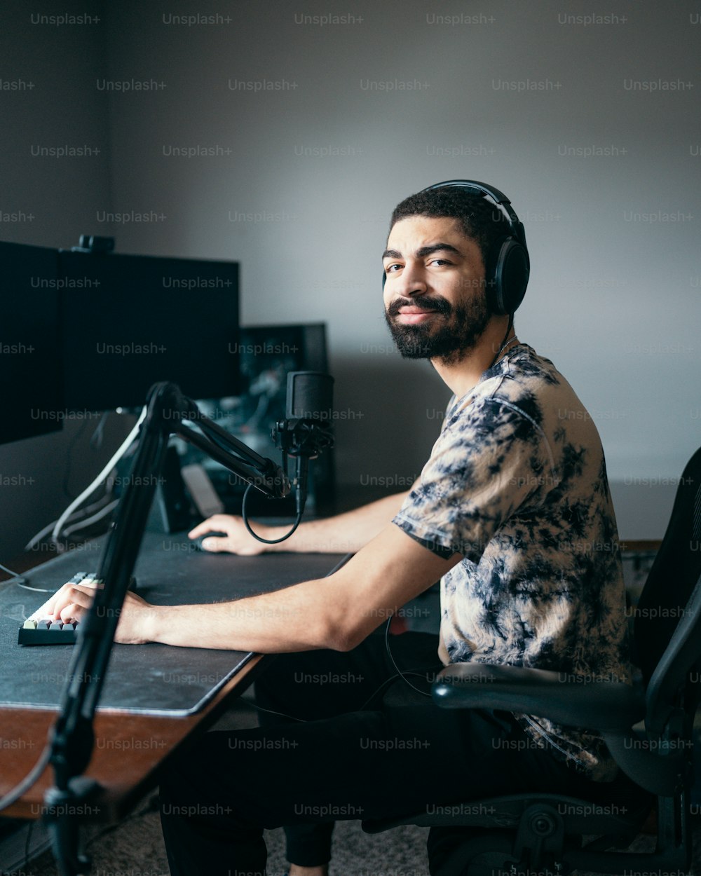 a man wearing headphones sitting at a desk in front of a microphone