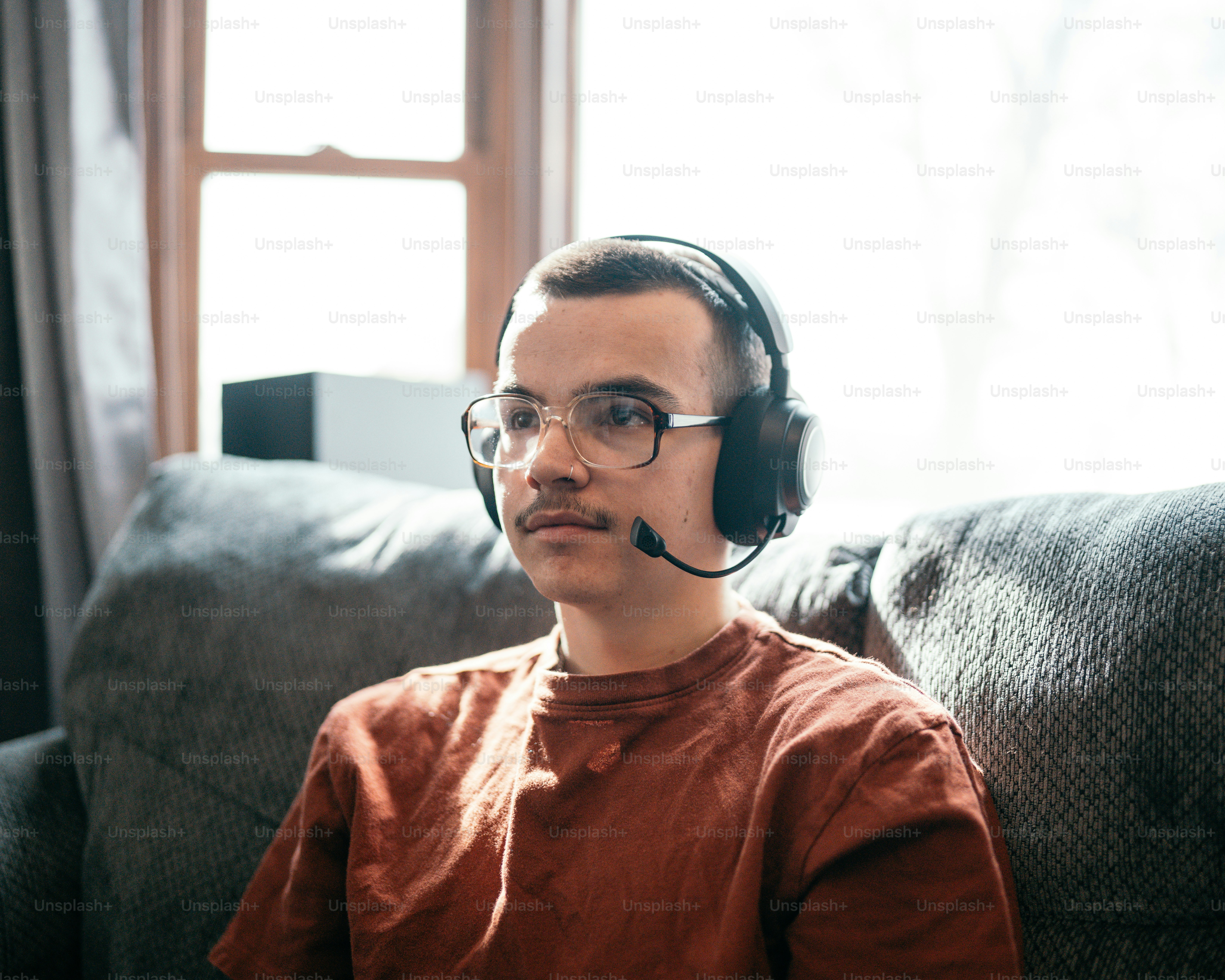 seorang pria duduk di sofa mengenakan headset