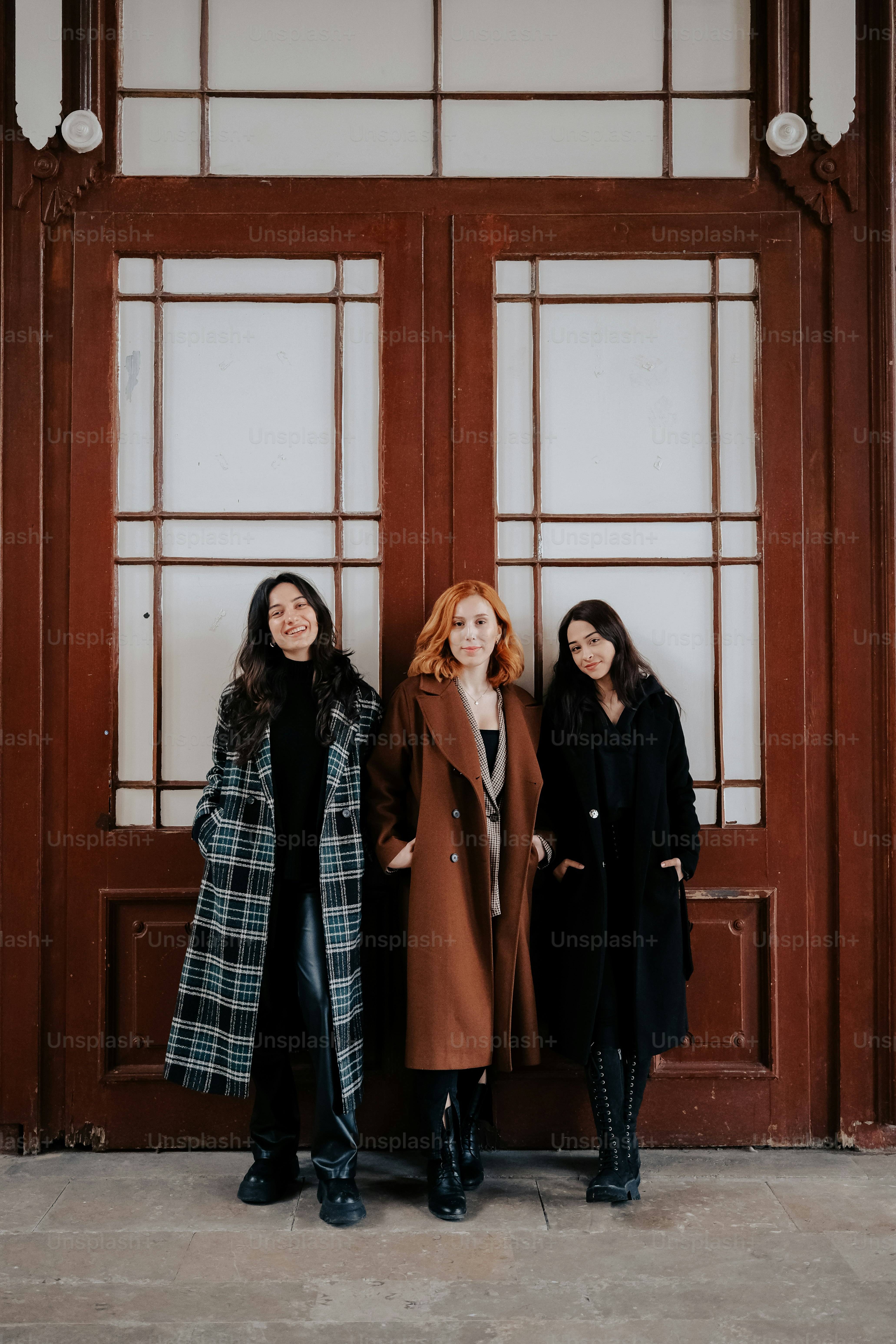 two women standing next to each other in front of a door