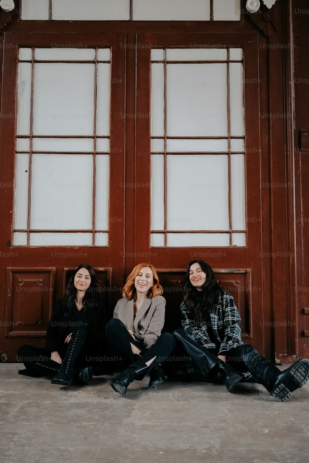 three women sitting on the ground in front of a door
