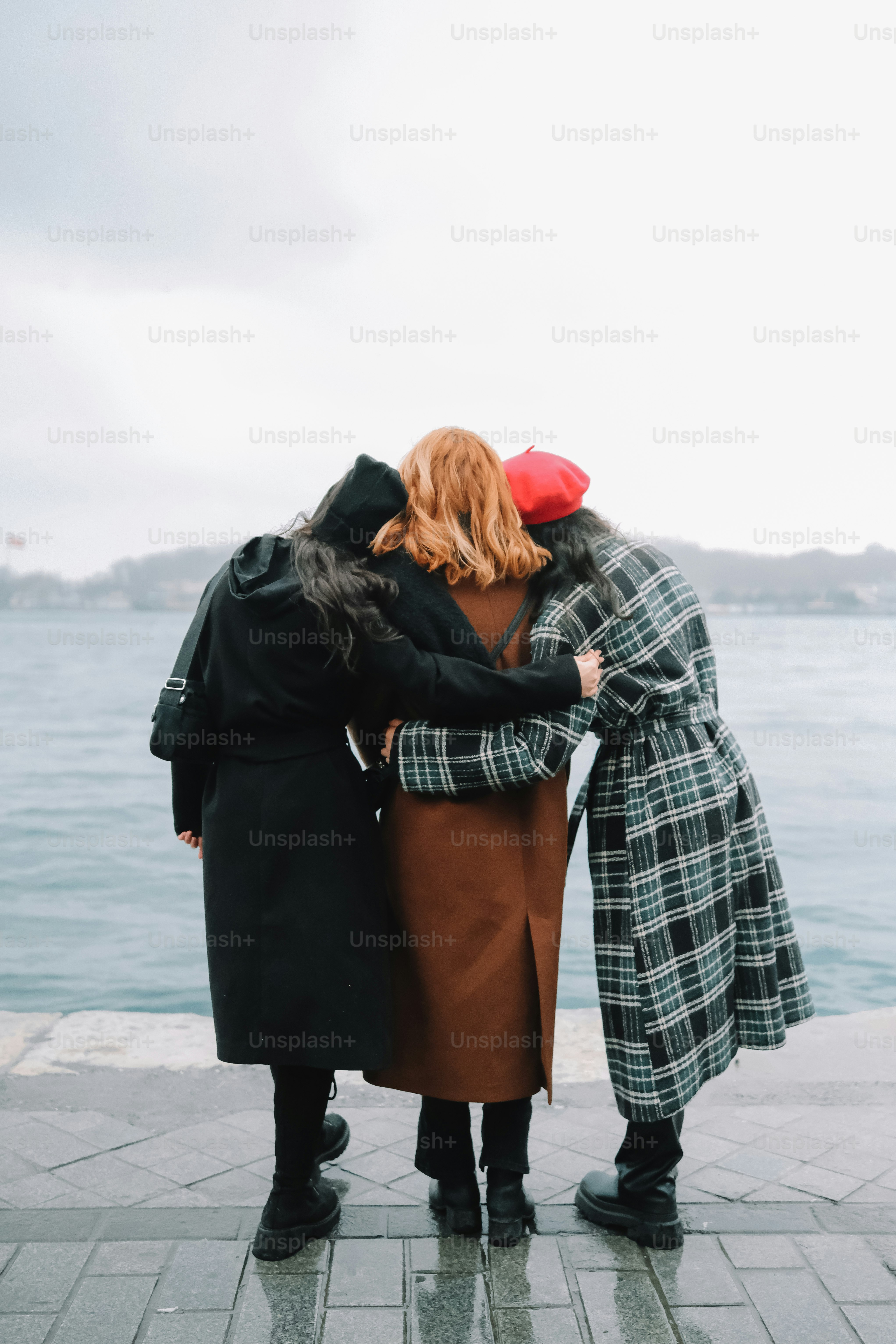 three women standing next to each other near a body of water