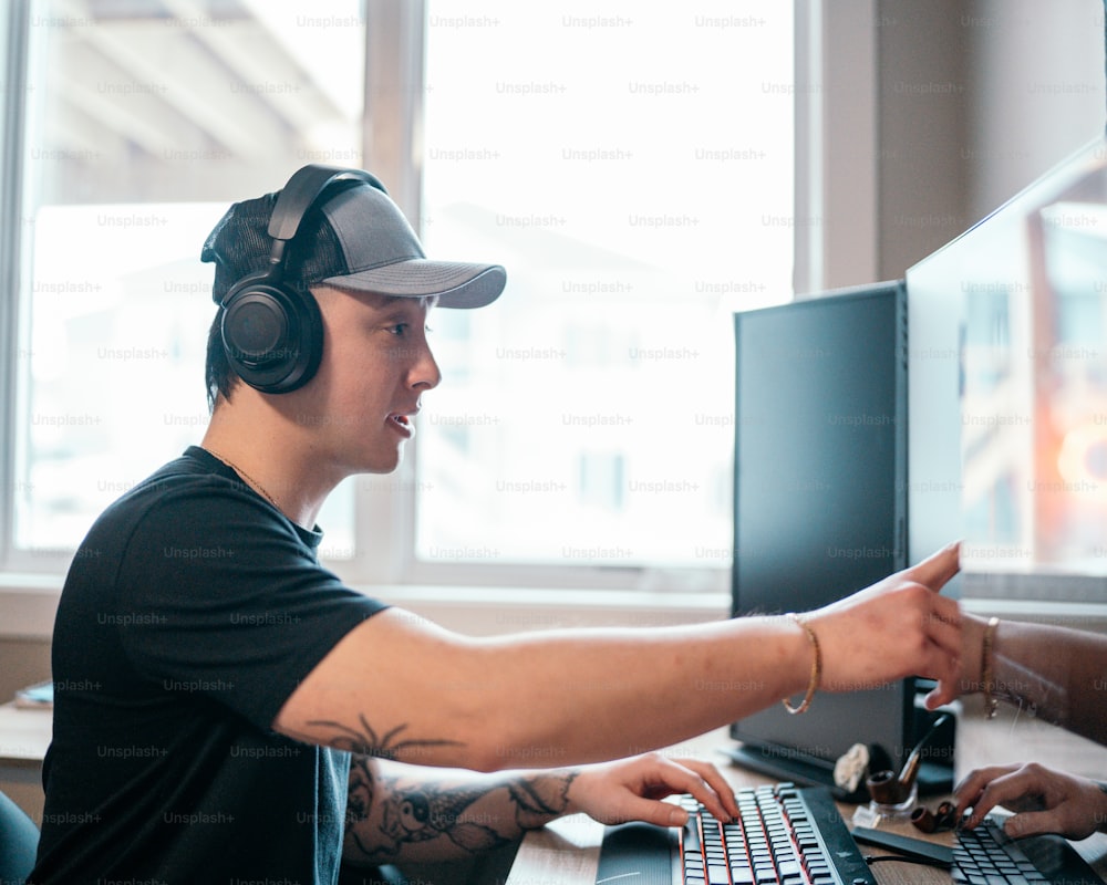 a man wearing headphones and pointing at a computer screen