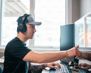 a man wearing headphones and pointing at a computer screen