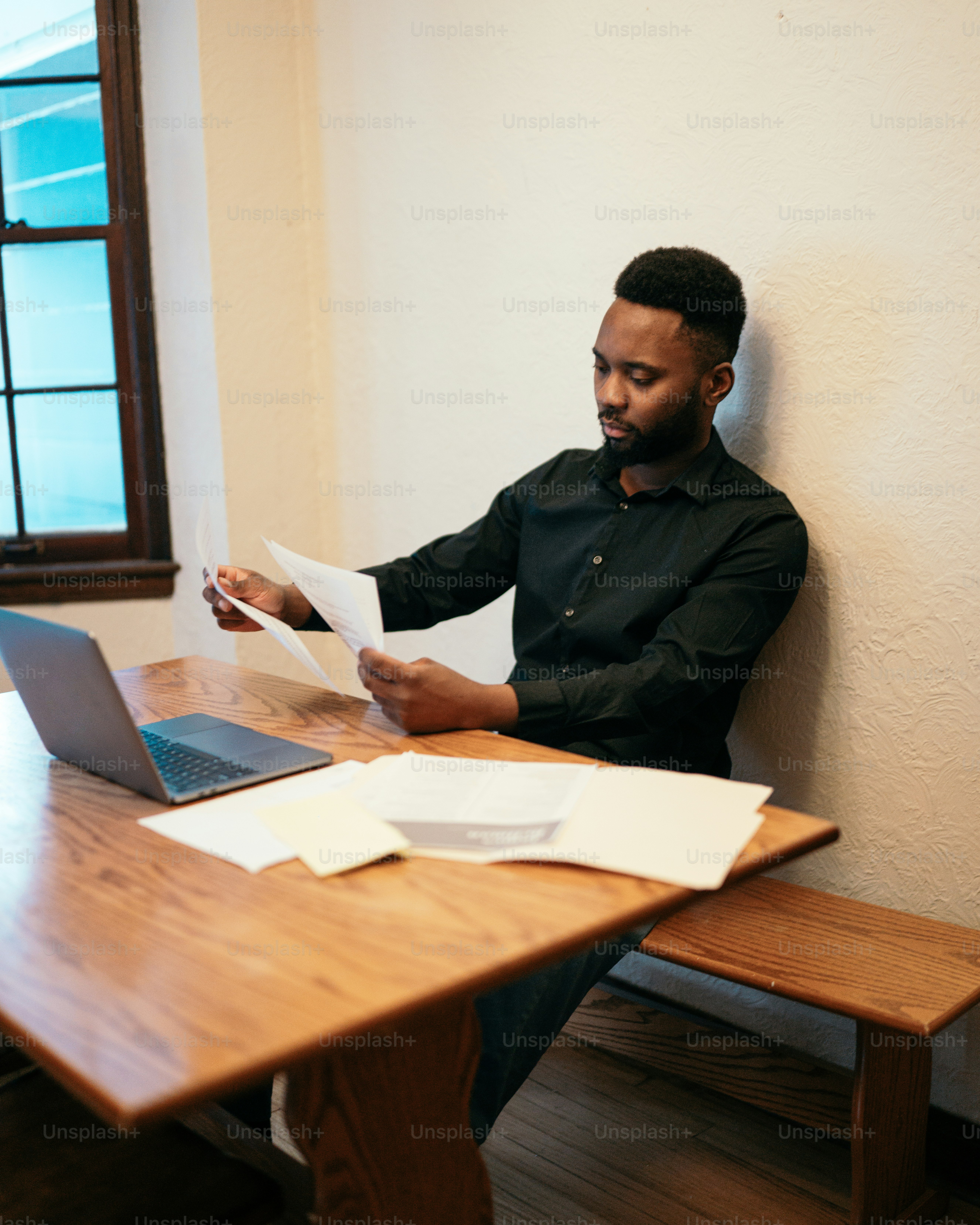 a man sitting at a table with a laptop and papers