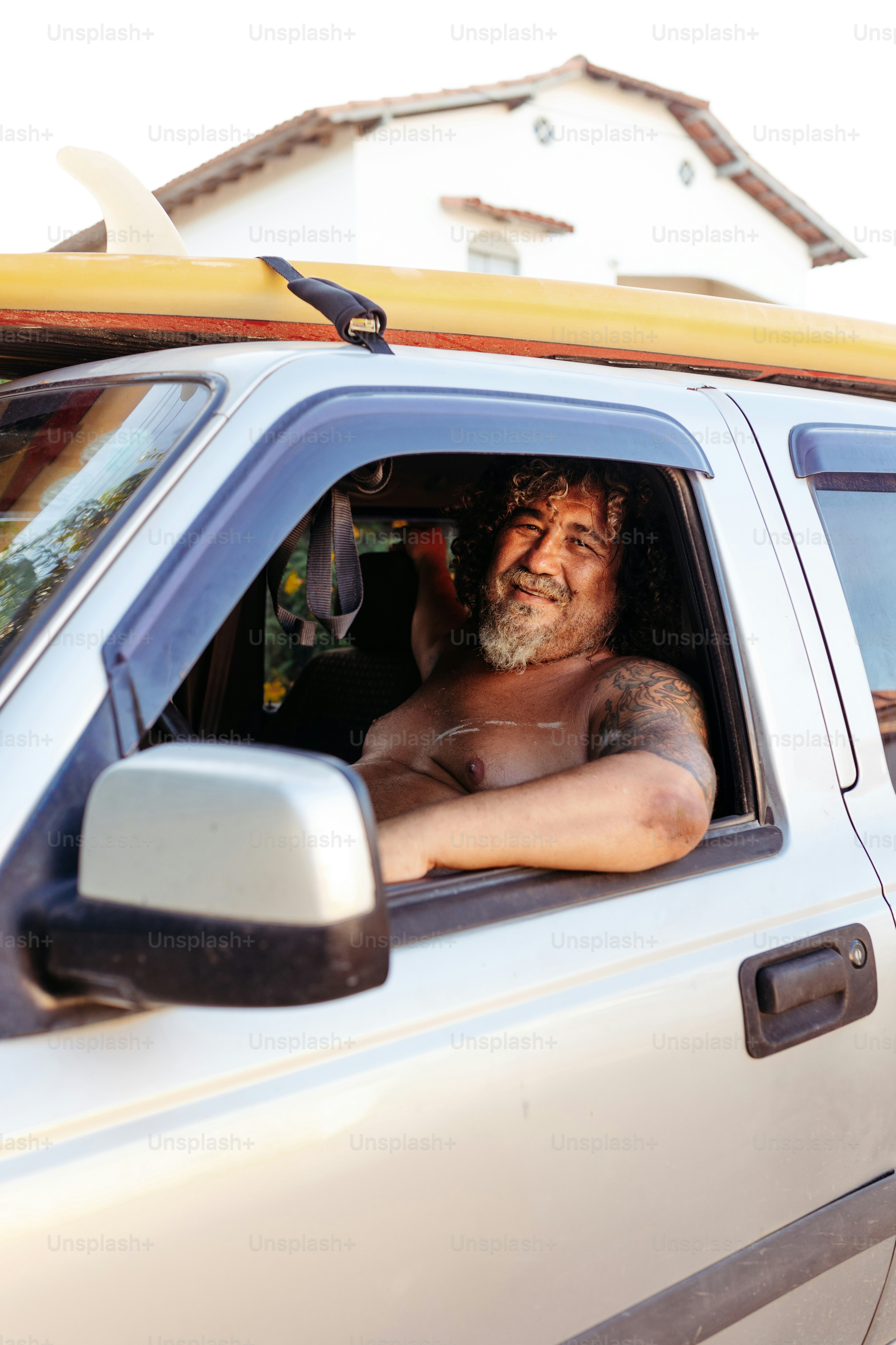 Un homme assis dans une voiture avec une planche de surf sur la tête