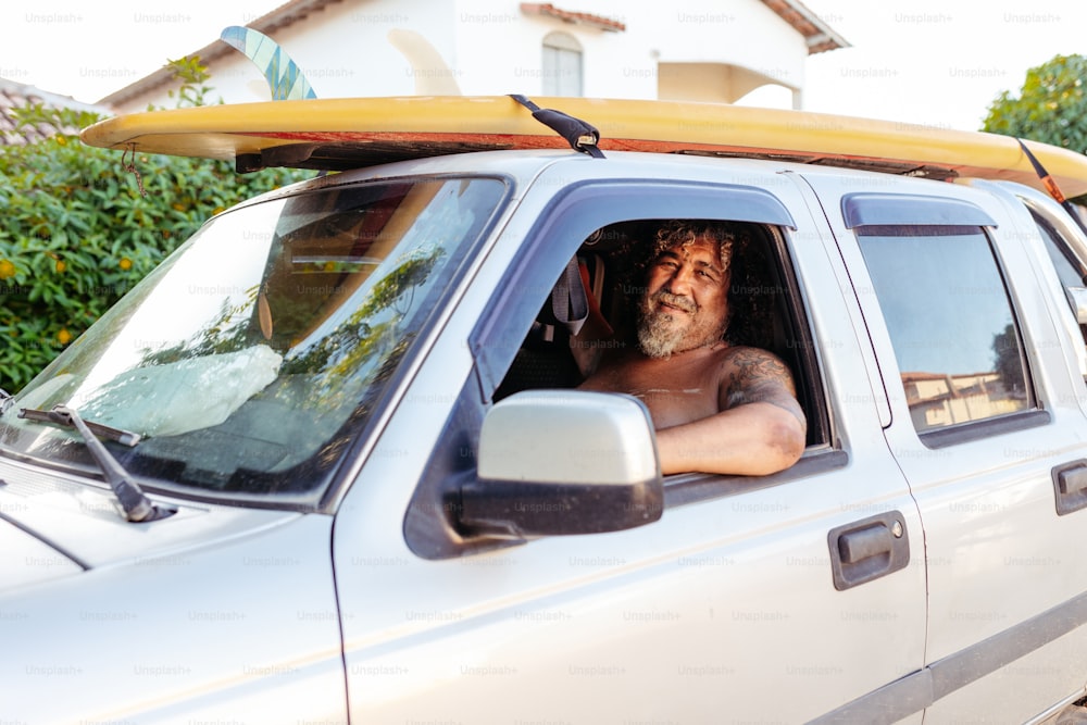 a man sitting in the back of a truck with a surfboard on top of
