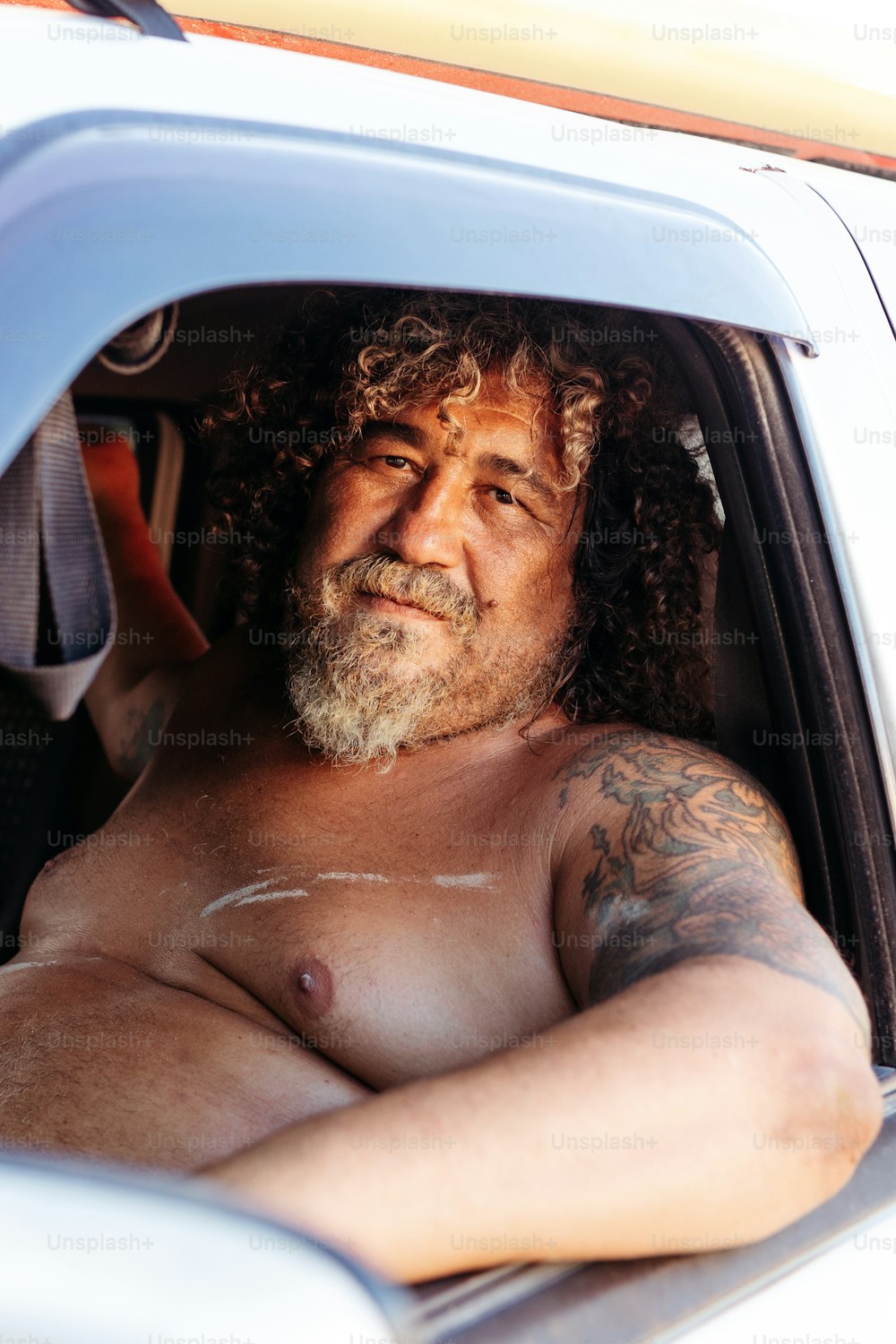 a man with long hair and a beard sitting in a car