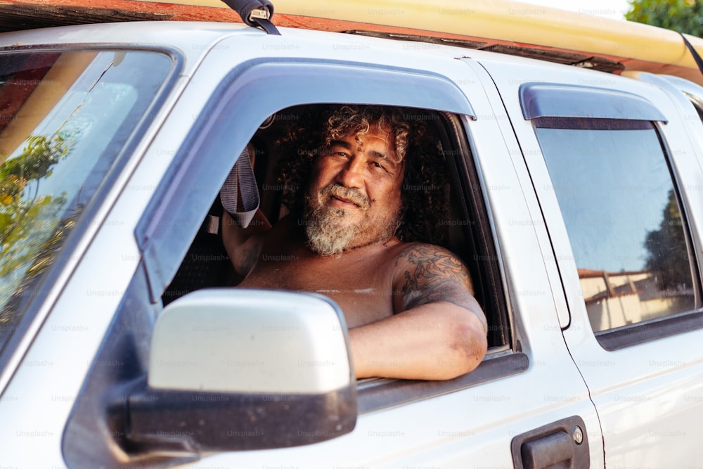 Un uomo in un camion bianco con una tavola da surf in cima alla testa