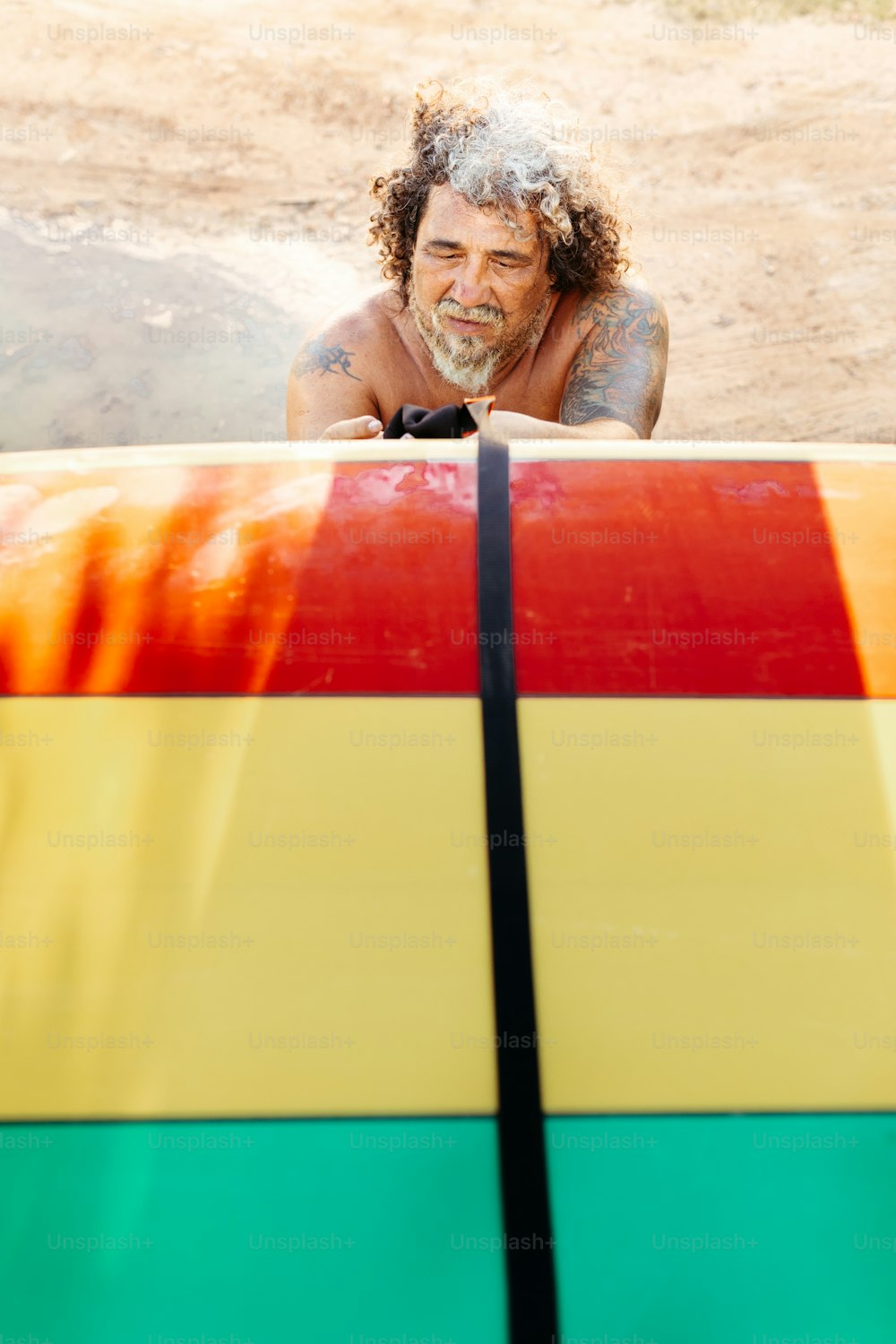 Un uomo appoggiato su una tavola da surf nella sabbia