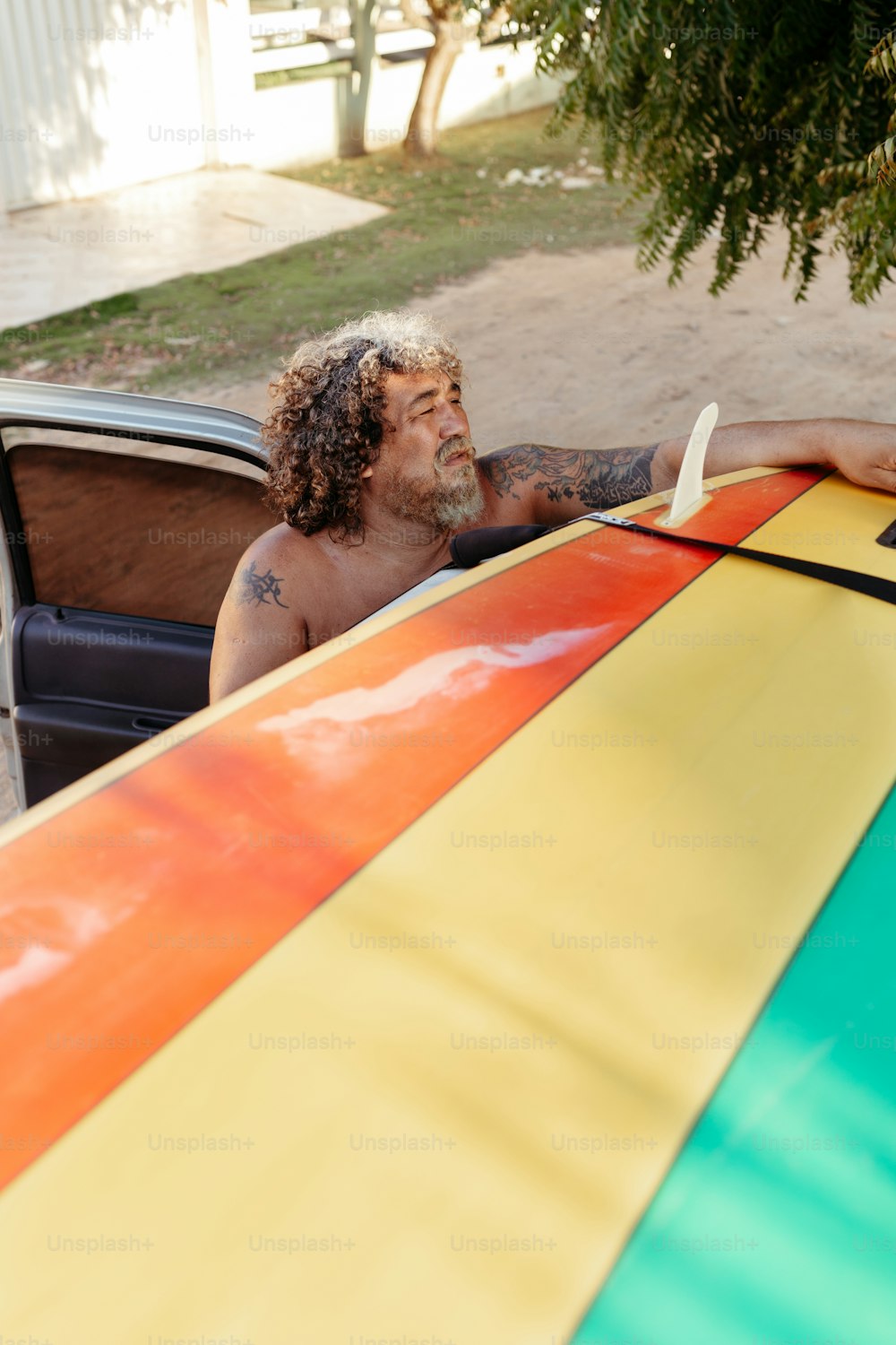 a man sitting in the back of a car holding a surfboard