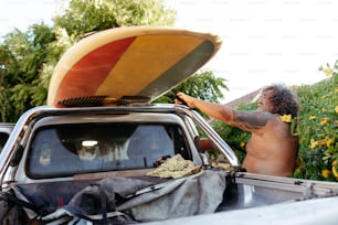 Un hombre con una tabla de surf encima de un camión