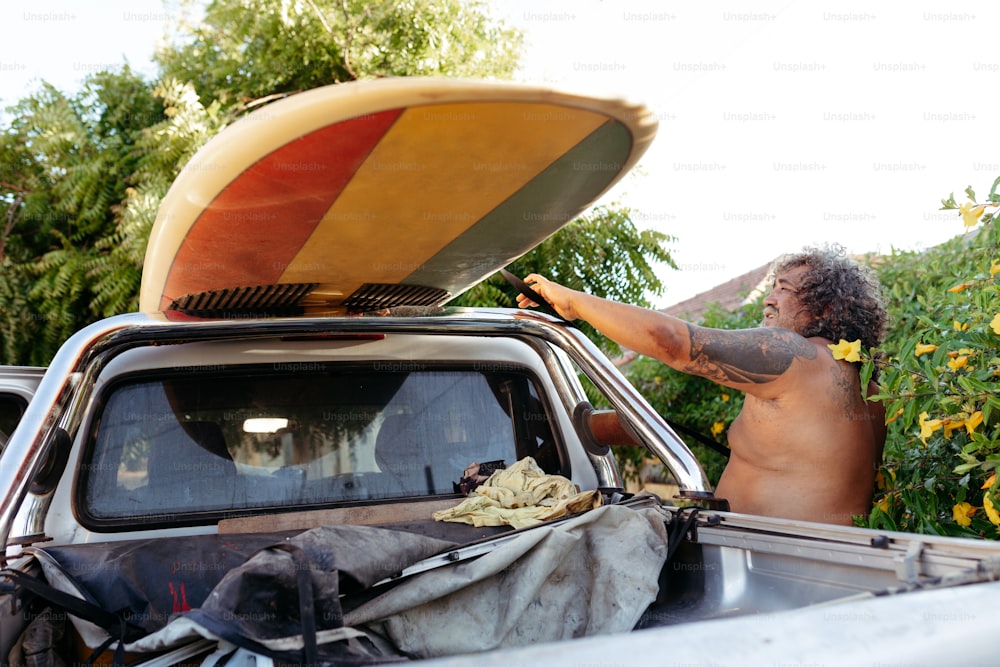Ein Mann mit einem Surfbrett auf dem Dach eines Lastwagens