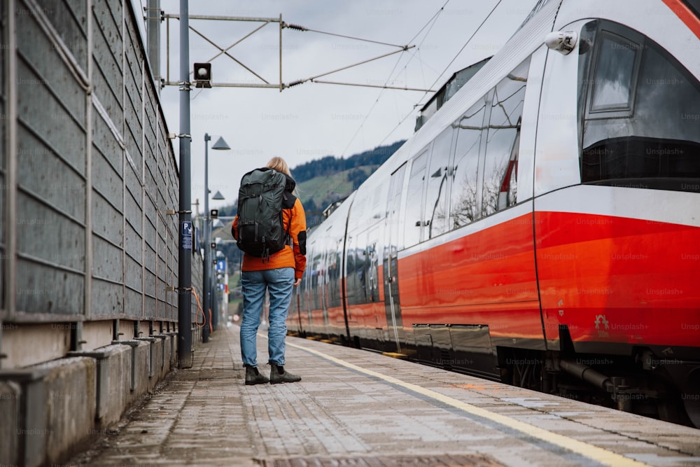 Un uomo con uno zaino sta aspettando un treno