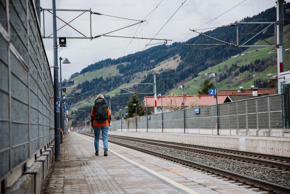a man walking down a train track next to a train station