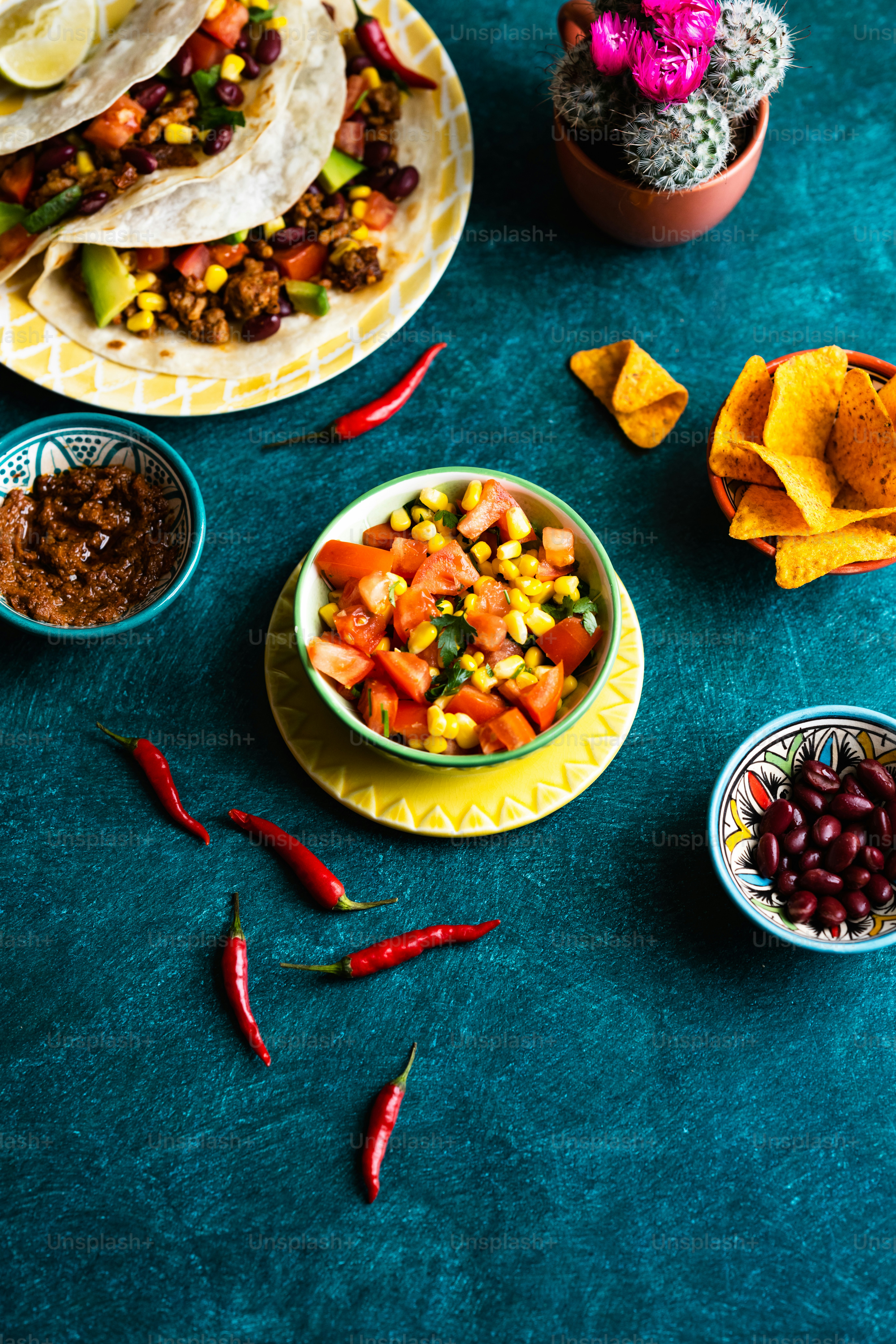 a table topped with plates of food and bowls of salsa