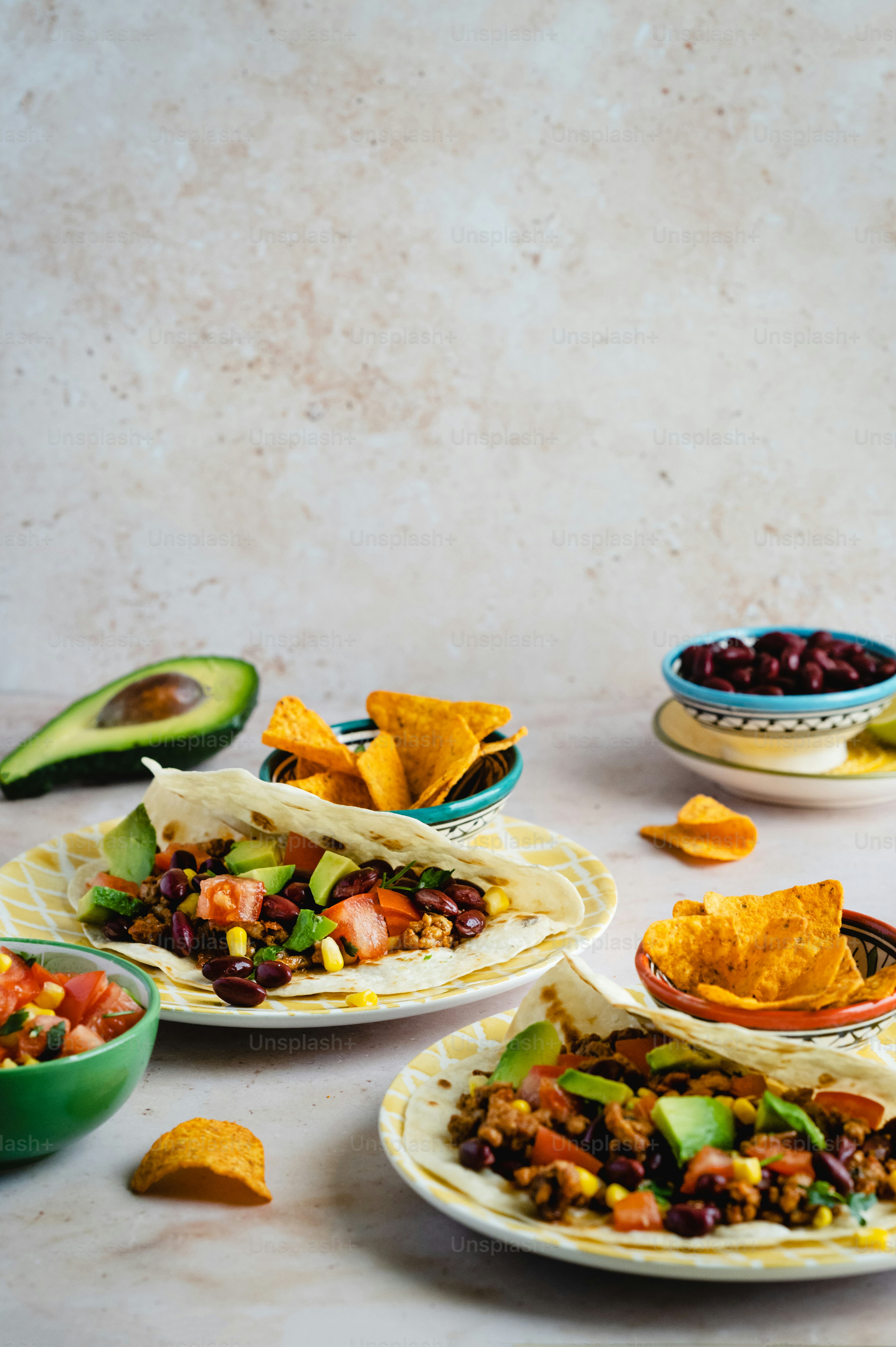 a table topped with plates of food and bowls of salsa