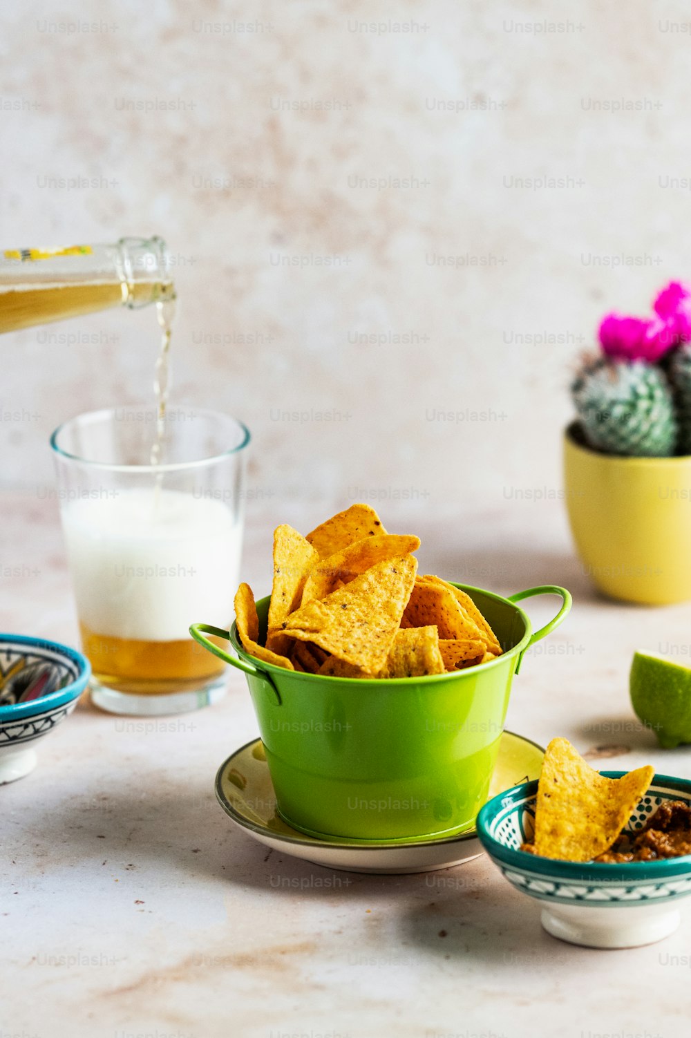 a green bowl filled with tortilla chips next to a glass of milk