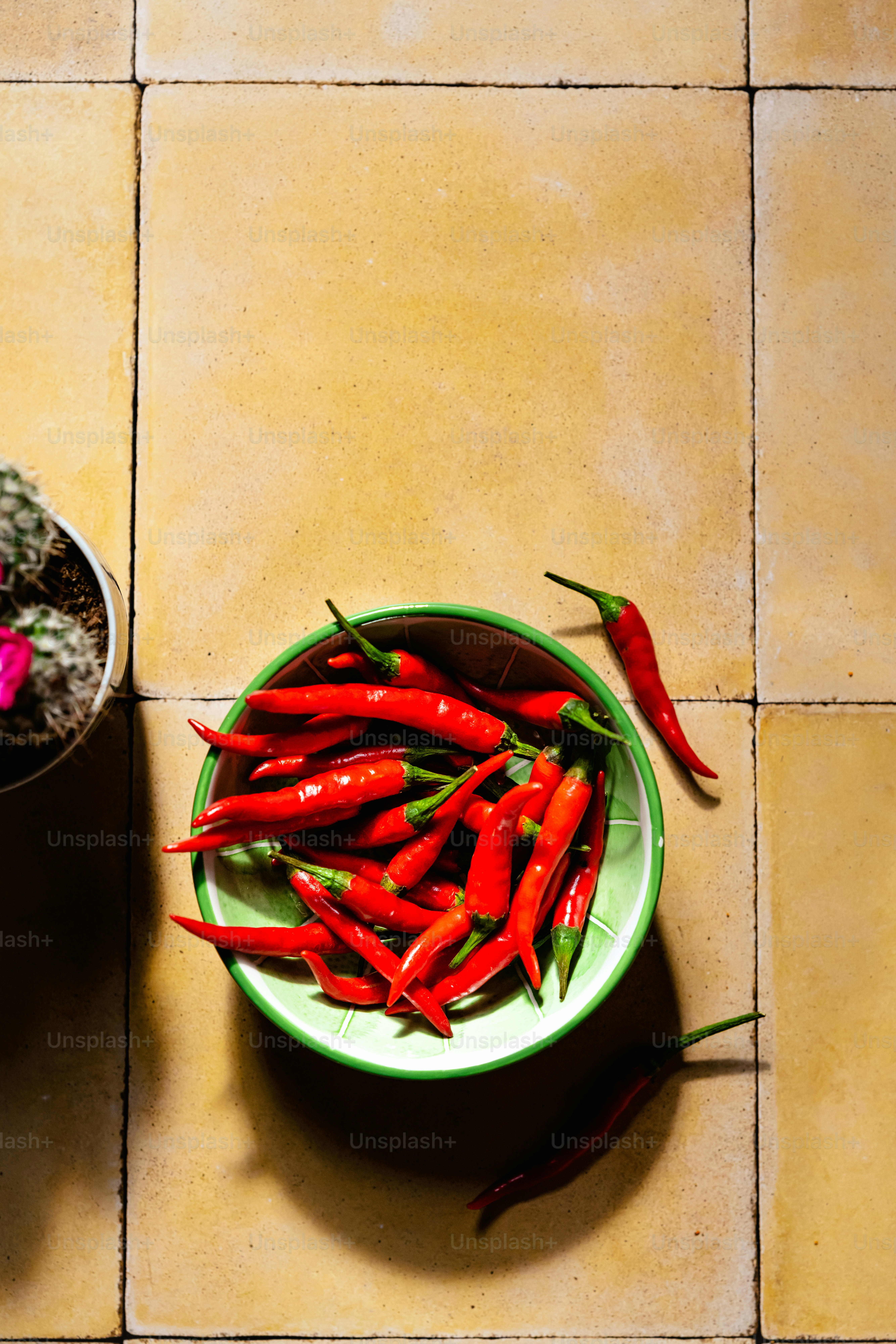 una ciotola di peperoni rossi seduti su un pavimento piastrellato