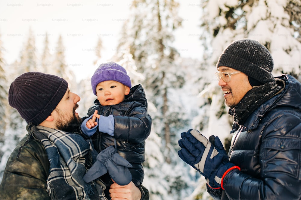 a man holding a baby in his arms while two other men look on