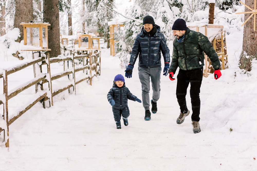 two adults and a child walking in the snow