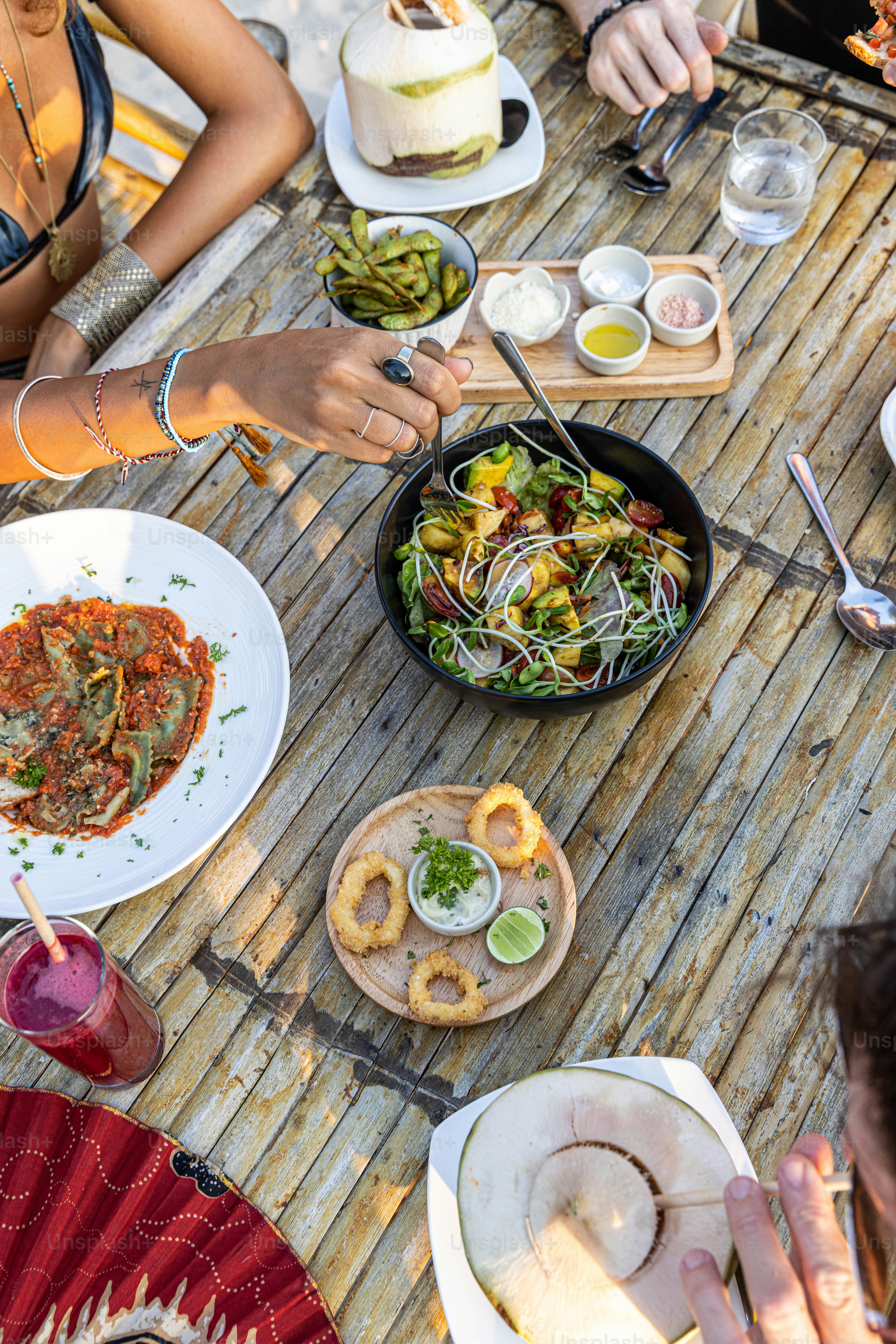 A group of people sitting around a table eating food photo – Sharing ...