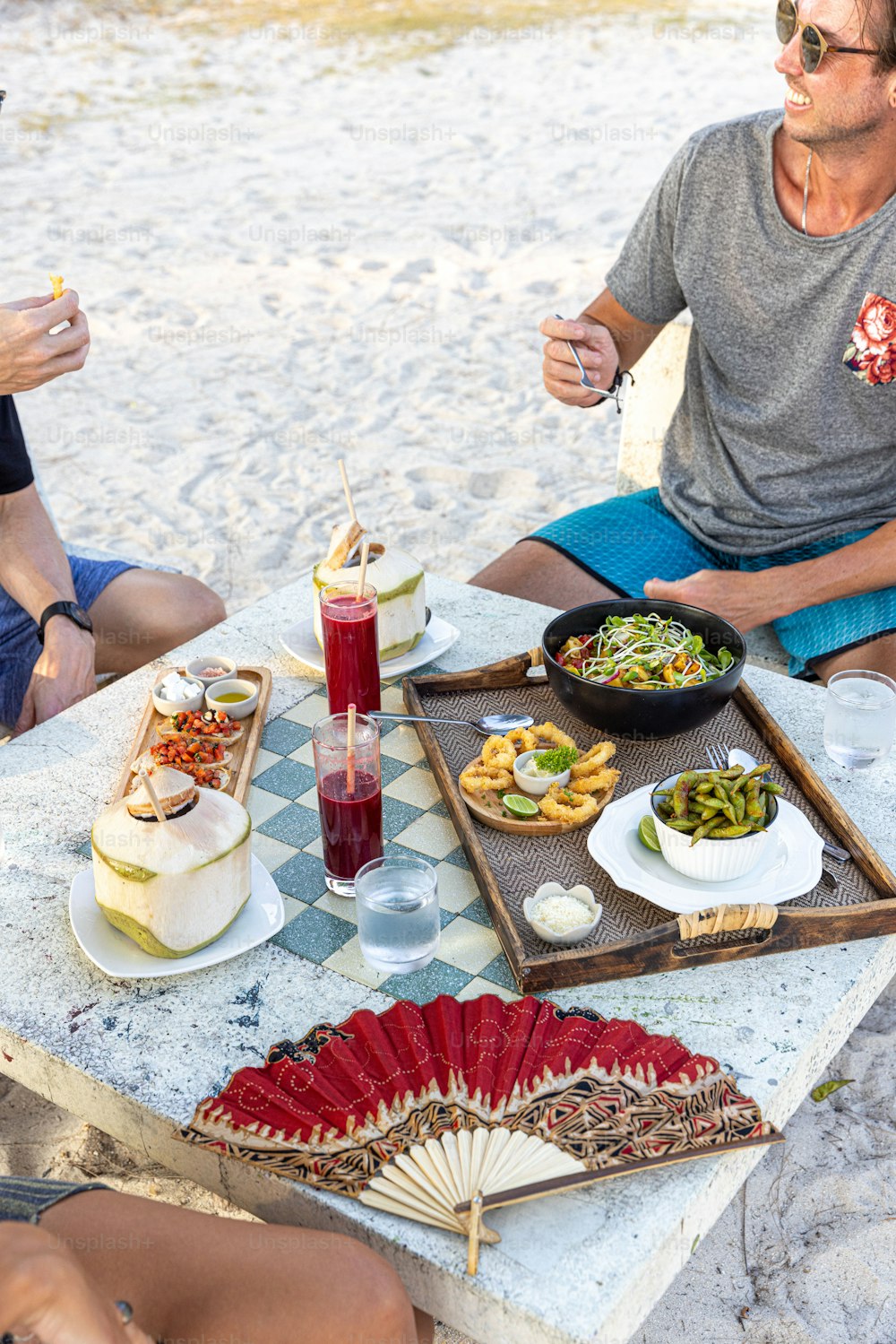um grupo de pessoas sentadas ao redor de uma mesa com comida sobre ela