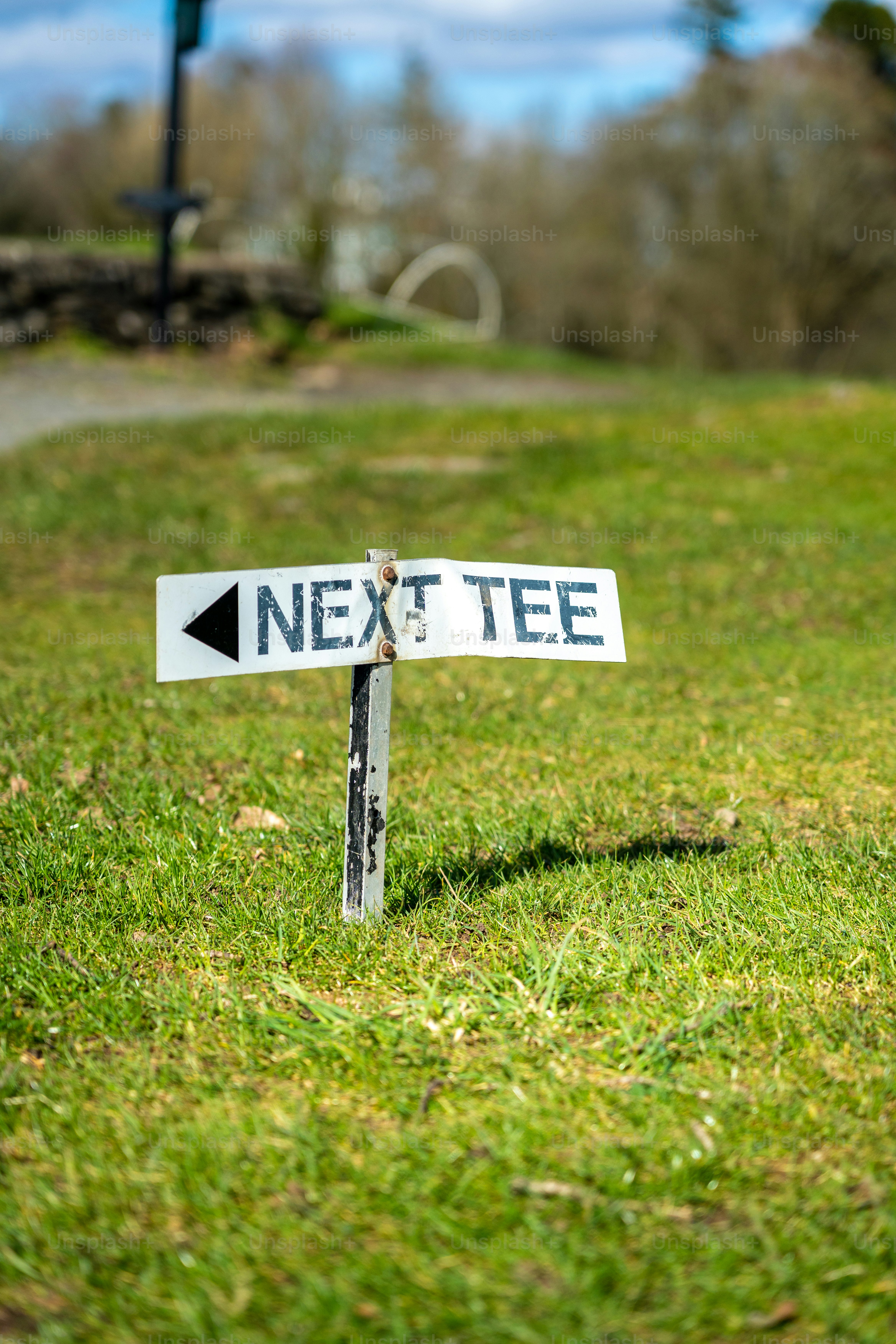 a white street sign sitting on top of a lush green field